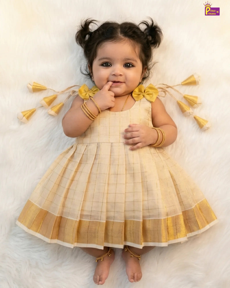 Baby girl in a yellow and white checkered dress with decorative elements on a light background