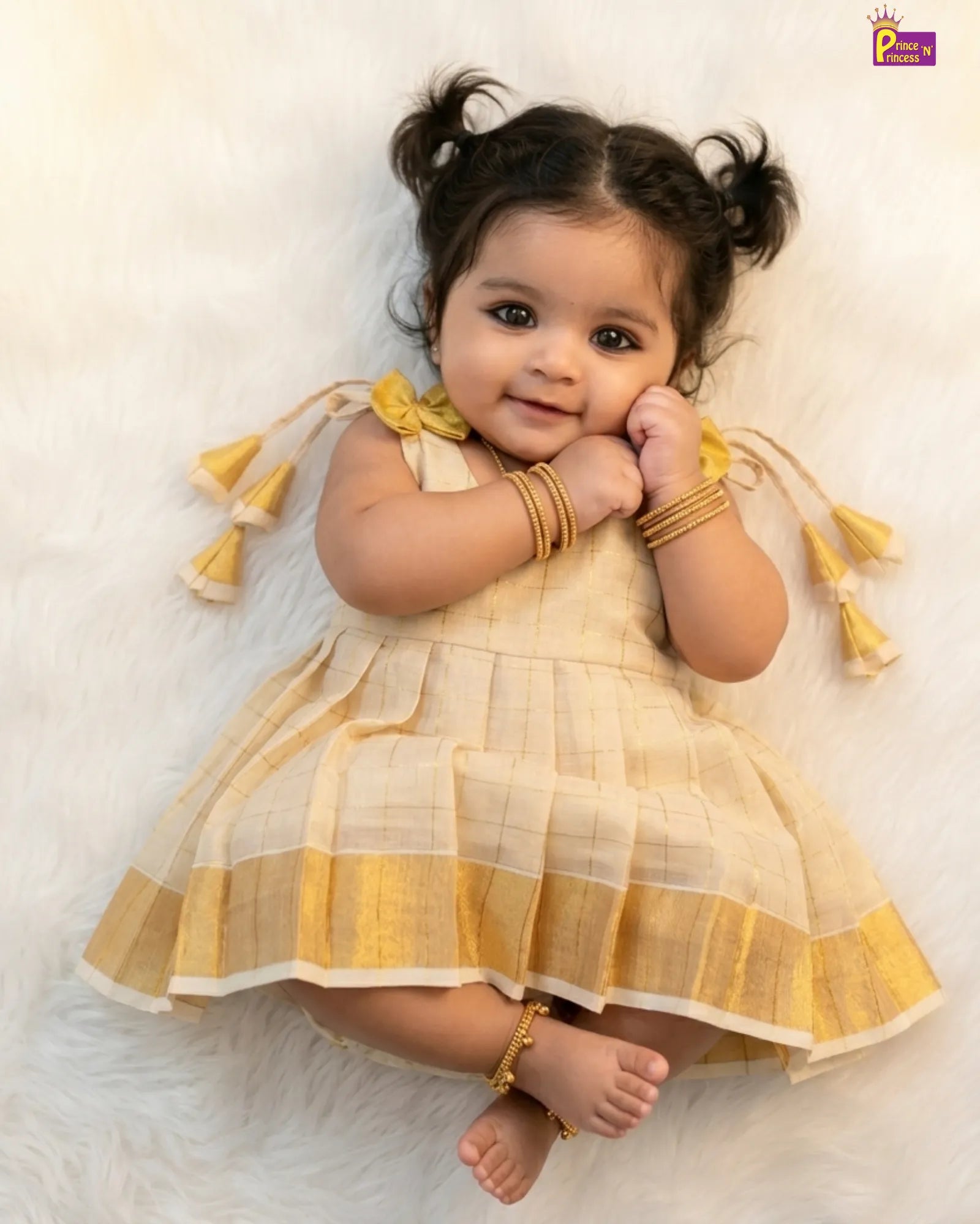 Baby in a yellow and white checkered dress with tassels on a light background