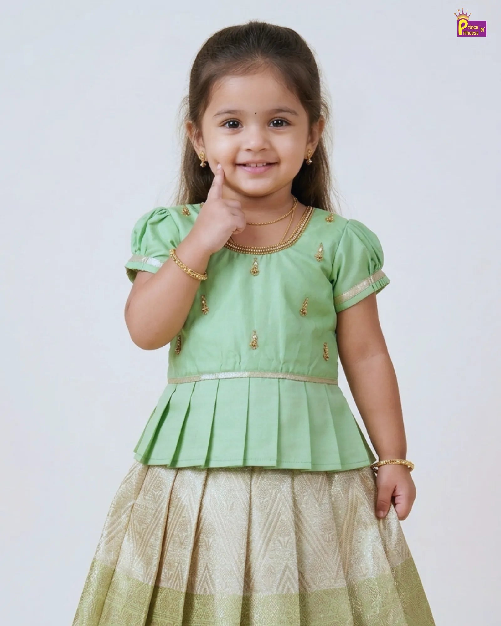 Young girl wearing a green traditional outfit with a plain background
