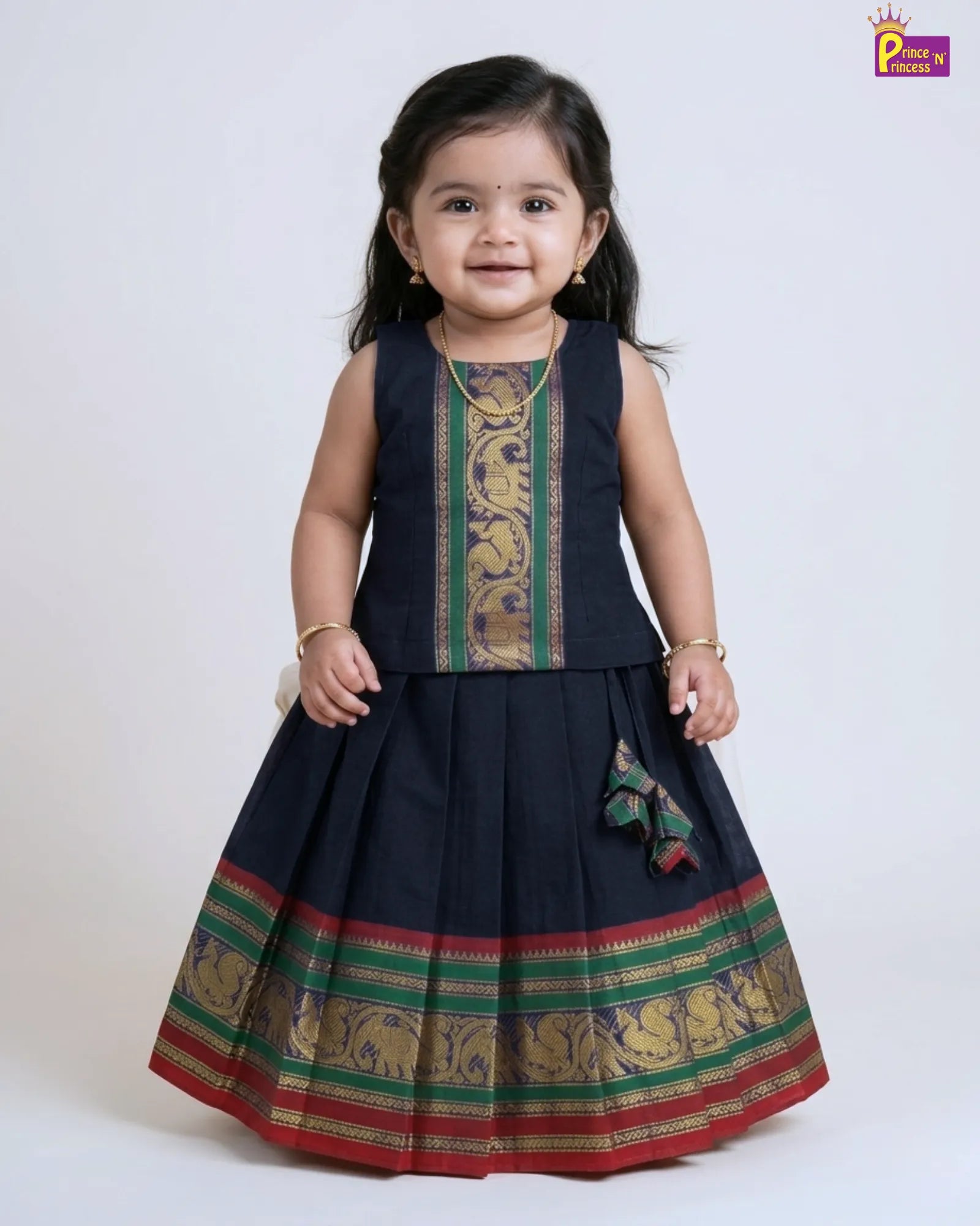 Child wearing a traditional black dress with colorful patterns on a white background