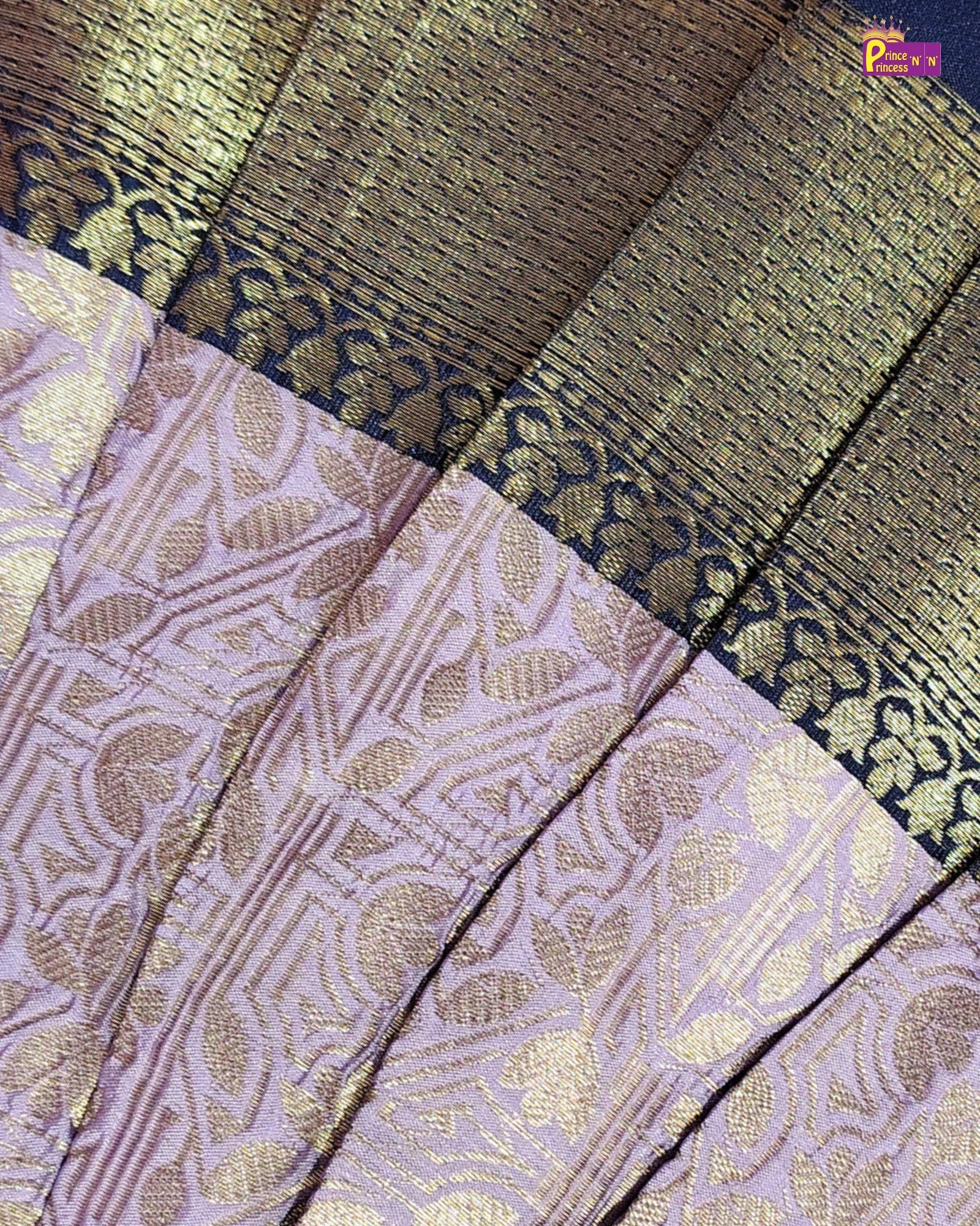 A close-up of a woven fabric, likely a saree, featuring a lavender-purple body with metallic gold floral patterns and a dark navy border with gold zari detailing.