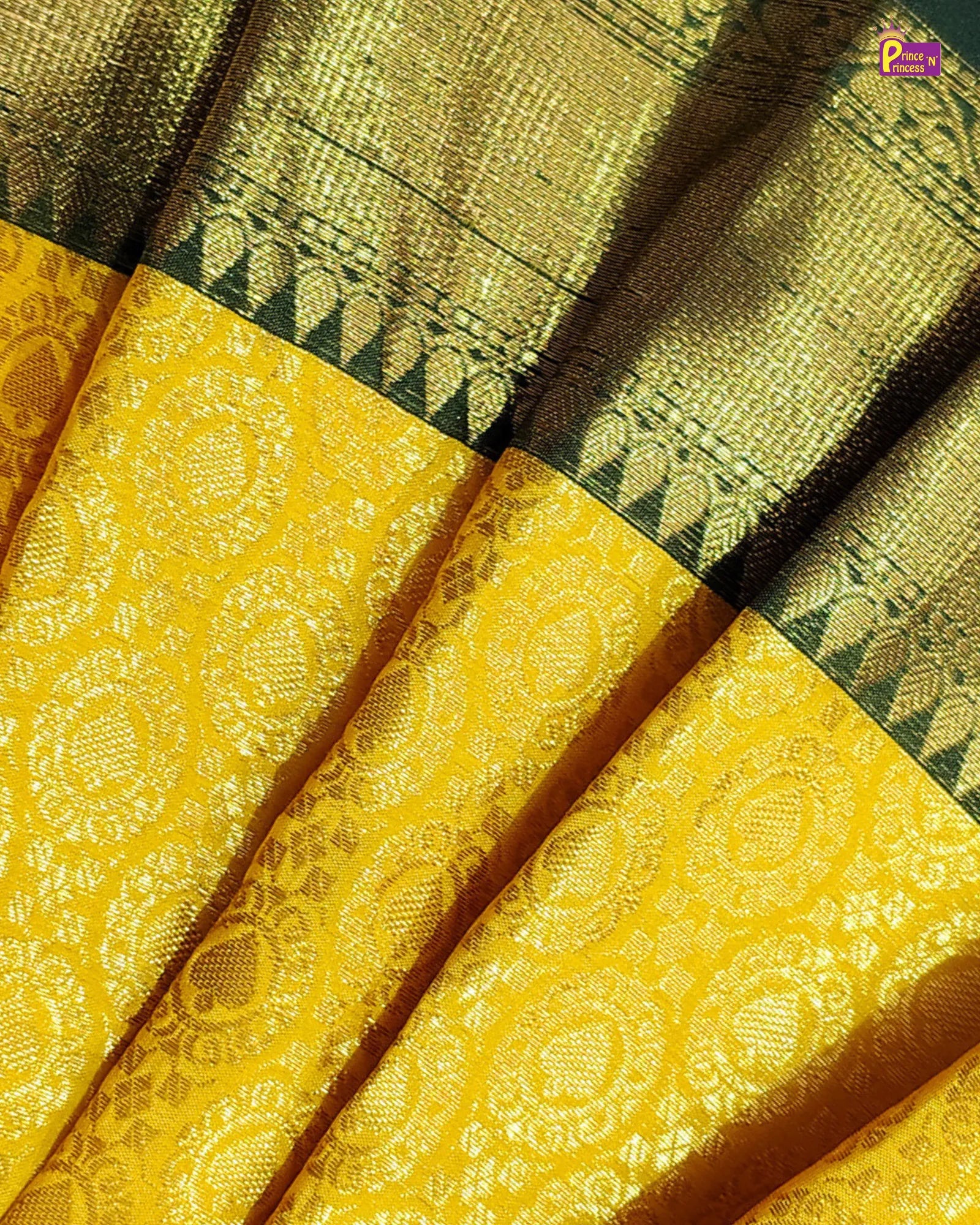 A close-up of a golden-yellow and black brocade fabric, showing detailed woven patterns and folds.