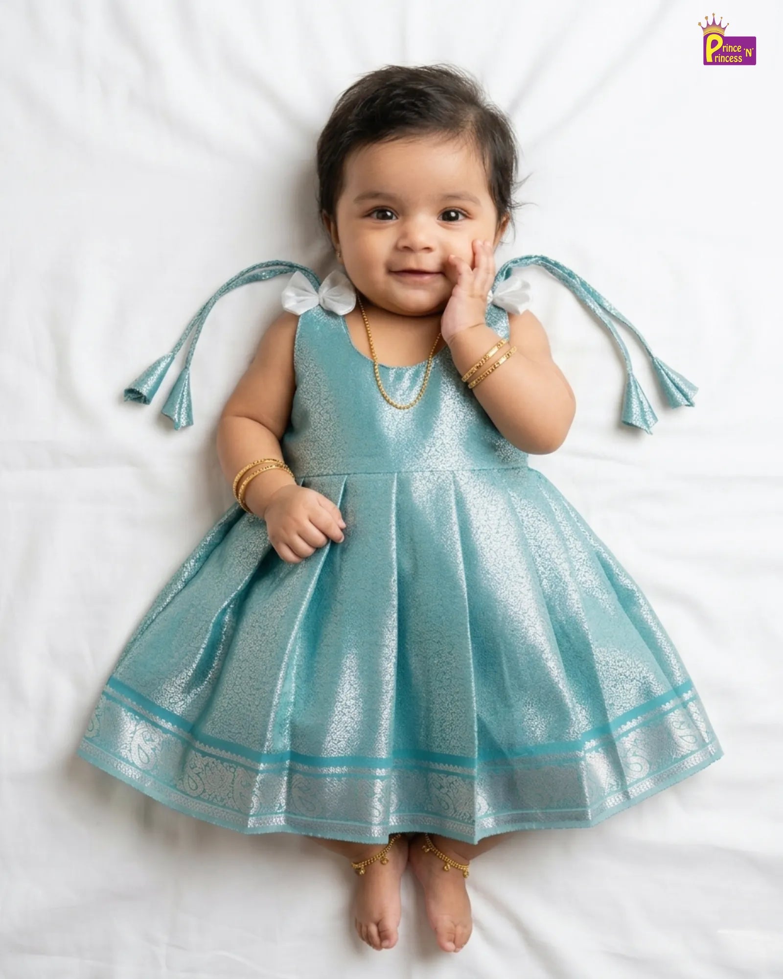 Baby wearing a blue dress with tassels on a white background