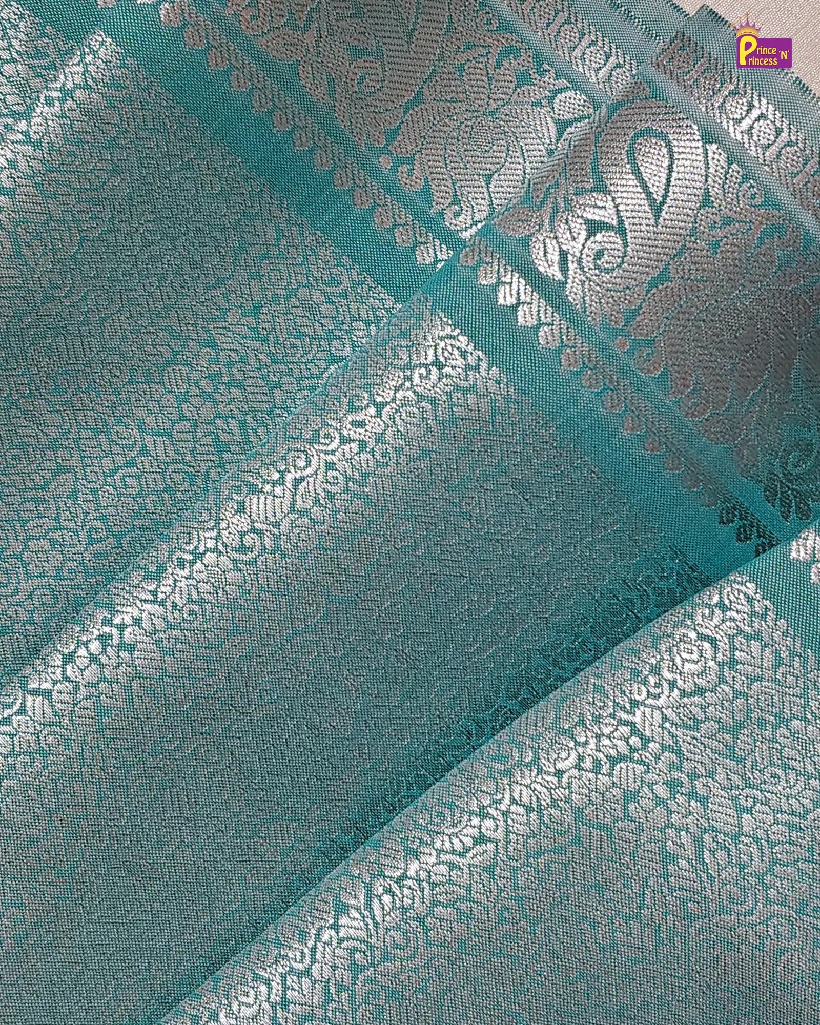 Teal fabric with silver floral patterns and a brand logo in the corner.
