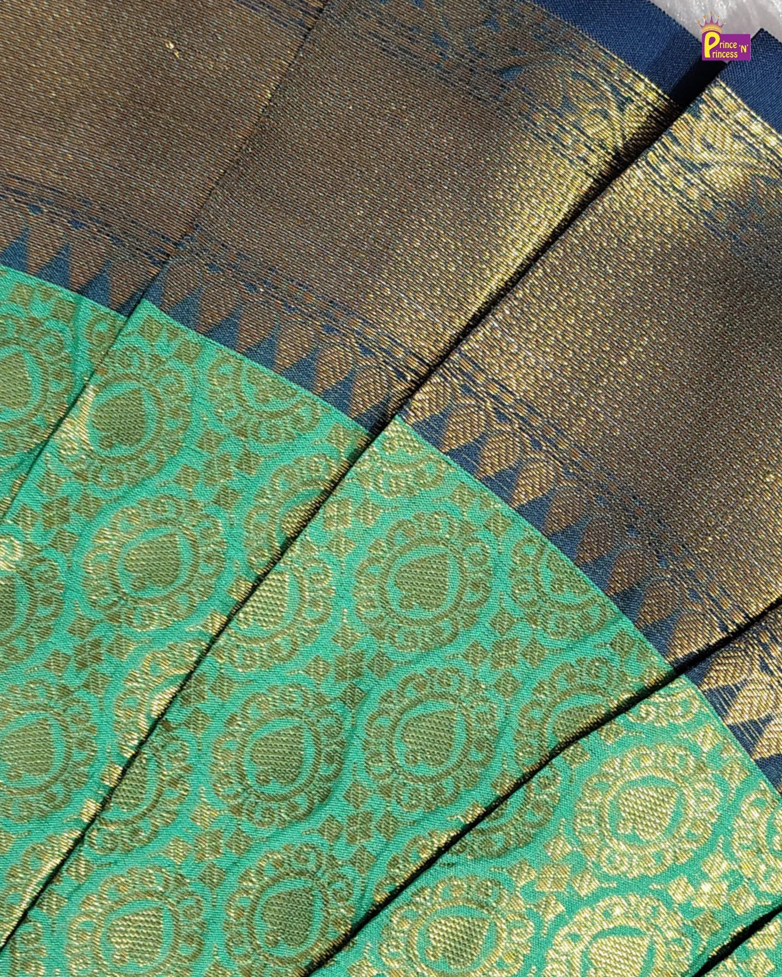 Close-up of a sari fabric showing a teal green body with gold zari motifs and a dark blue border with gold woven detailing.