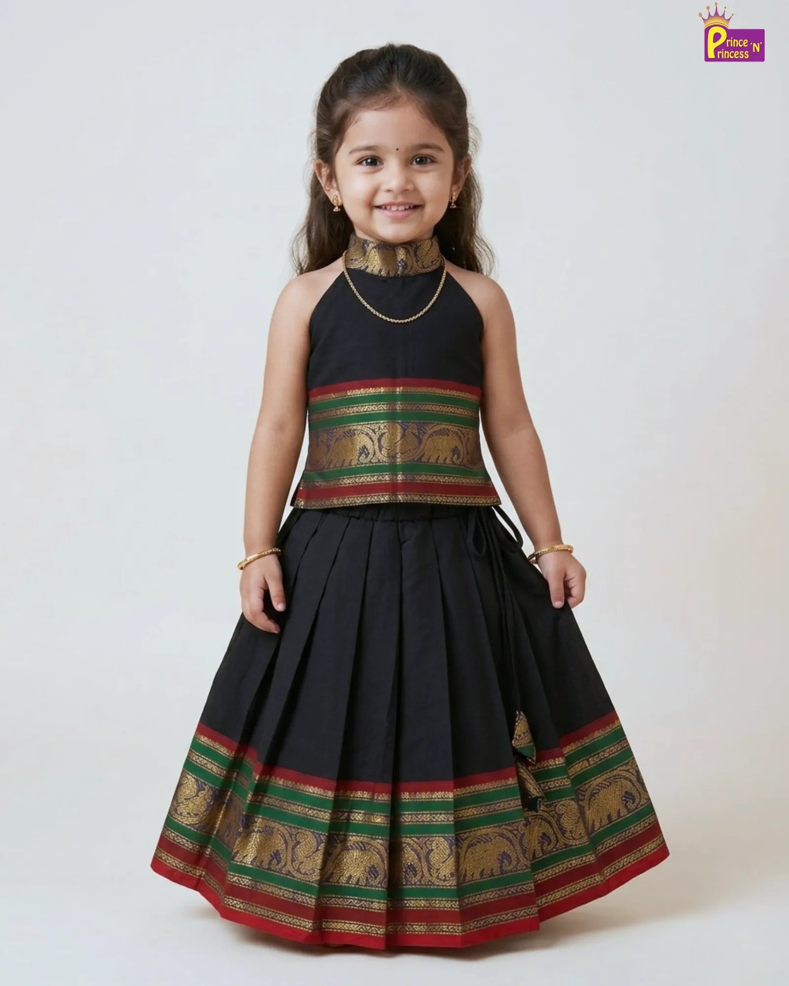 Young girl wearing a traditional black and gold dress with elephant patterns on a white background