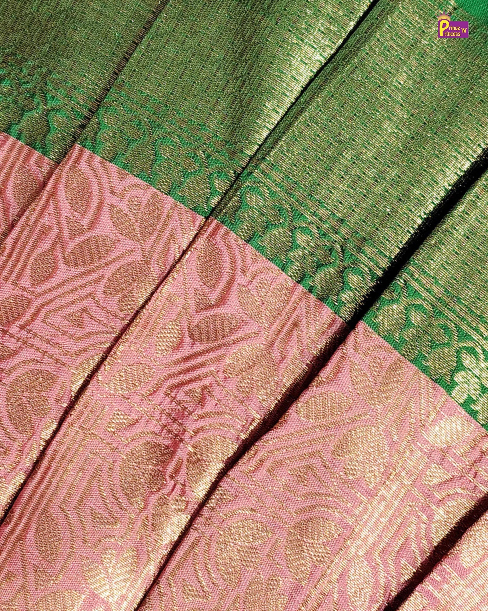 Close-up of a woven textile with a green upper section and a pink lower section, both featuring metallic gold zari floral and geometric patterns.
