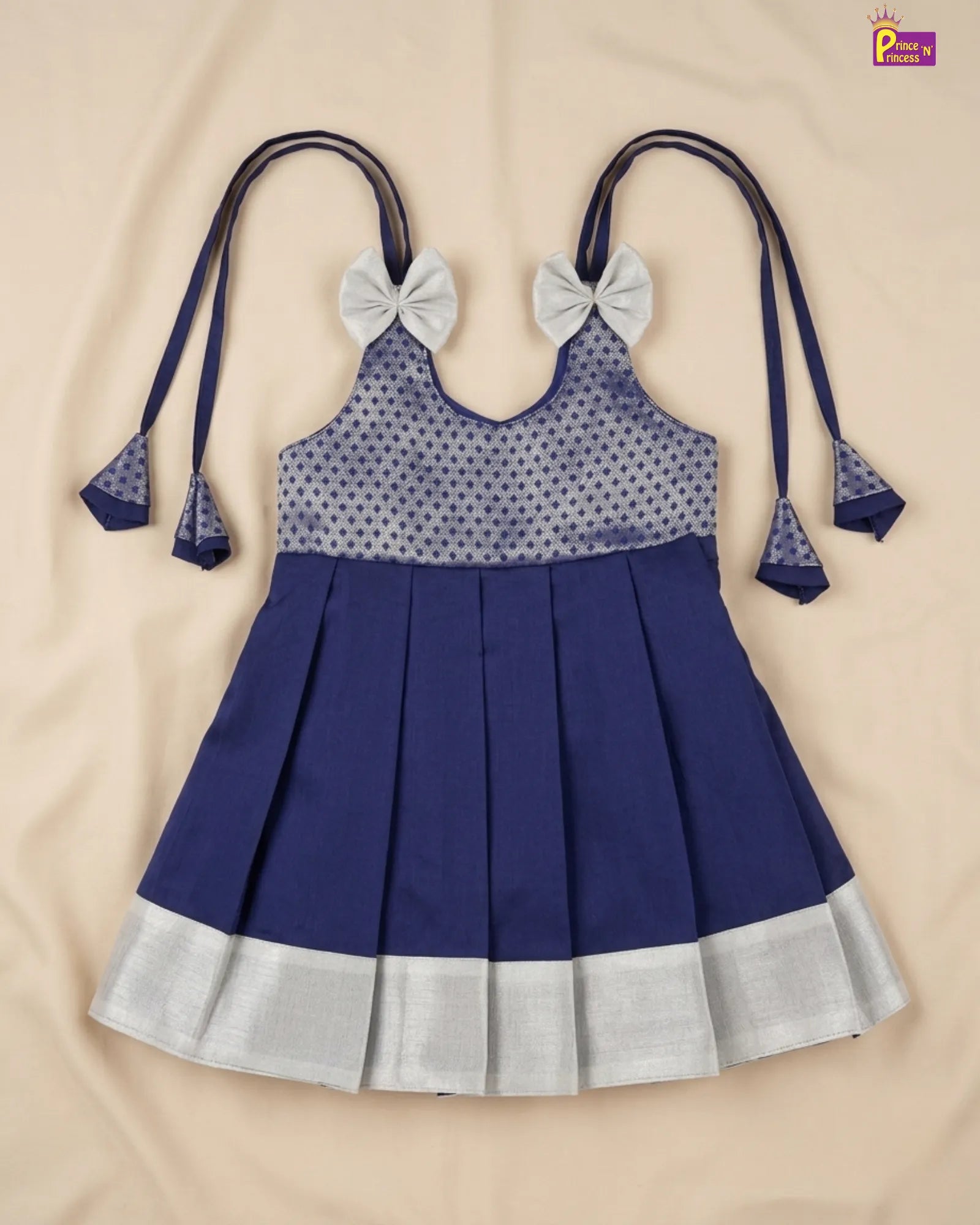 Blue and silver dress with bow straps on a beige background