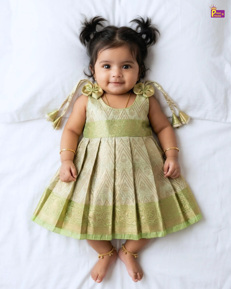 Baby wearing a green dress with decorative elements on a white background