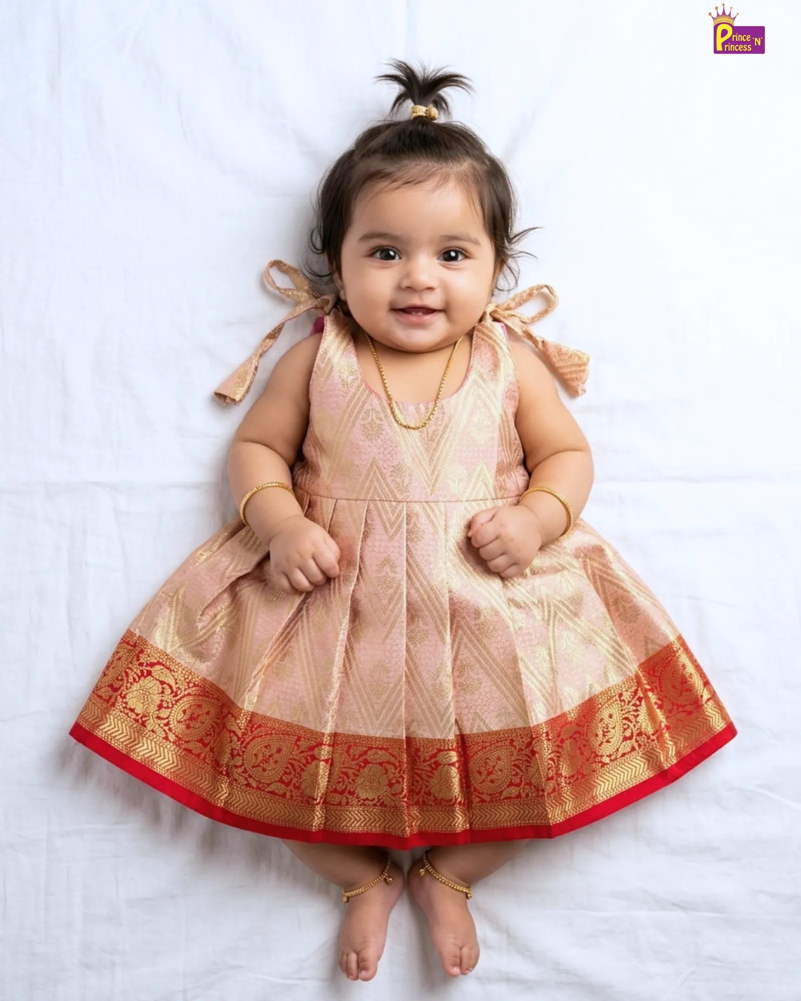 Baby wearing a traditional dress with intricate patterns on a white background