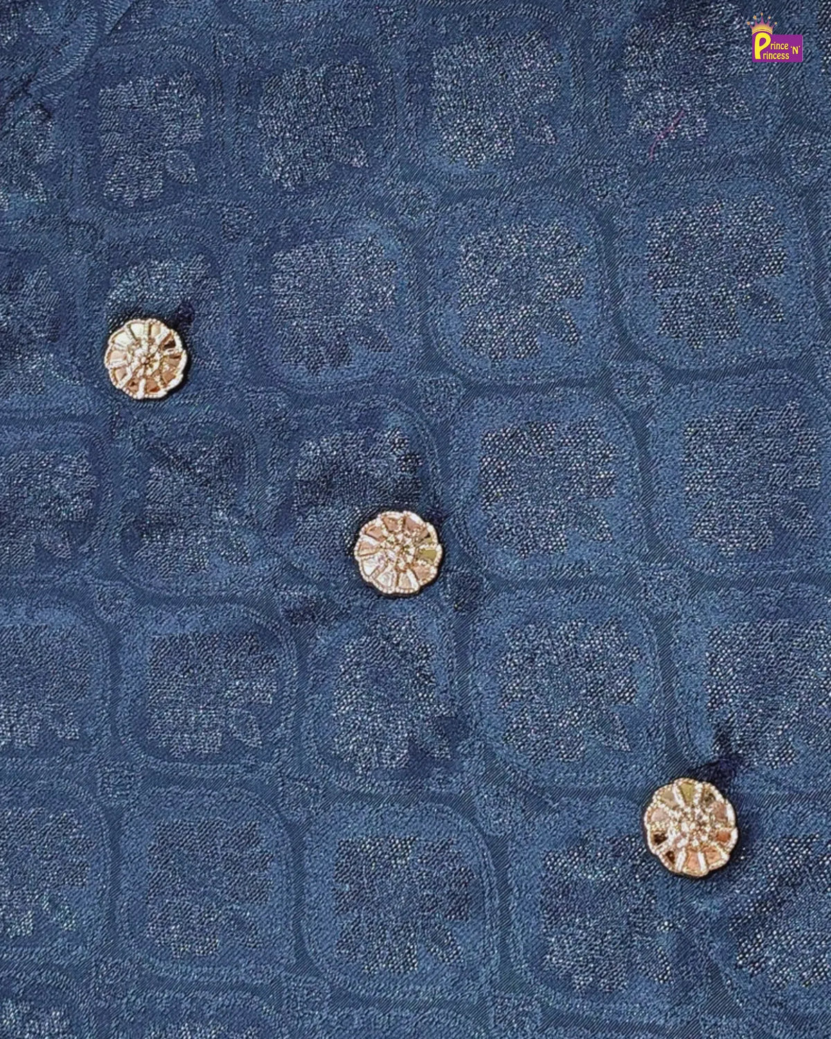 A close-up of a dark blue textured fabric with a repeating geometric and floral jacquard pattern, accented by three small metallic gold buttons.