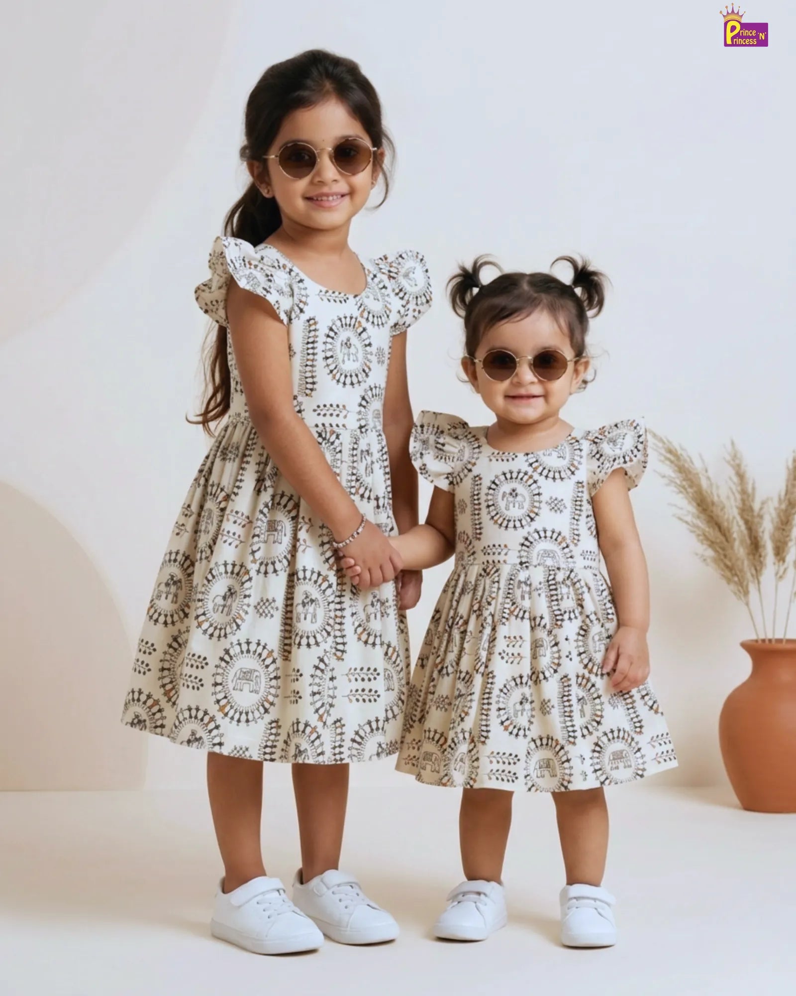 Baby girl in cream Kalamkari cotton dress with elephant tribal print and double ruffle flutter sleeves by Prince N Princess kids collection