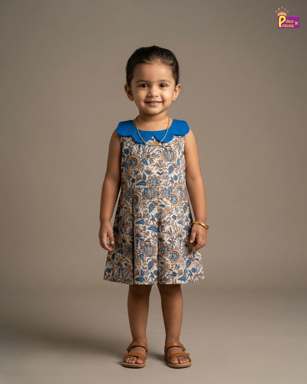 Young girl wearing a patterned dress with a blue collar against a plain background - Prince N Princess