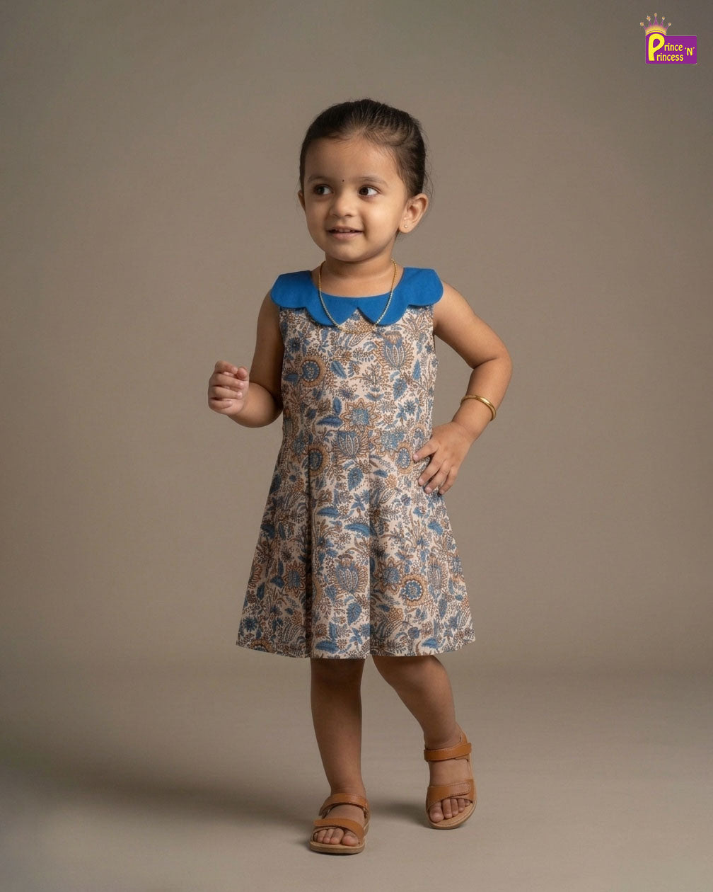Child wearing a floral dress with a blue collar against a brown background - Prince N Princess