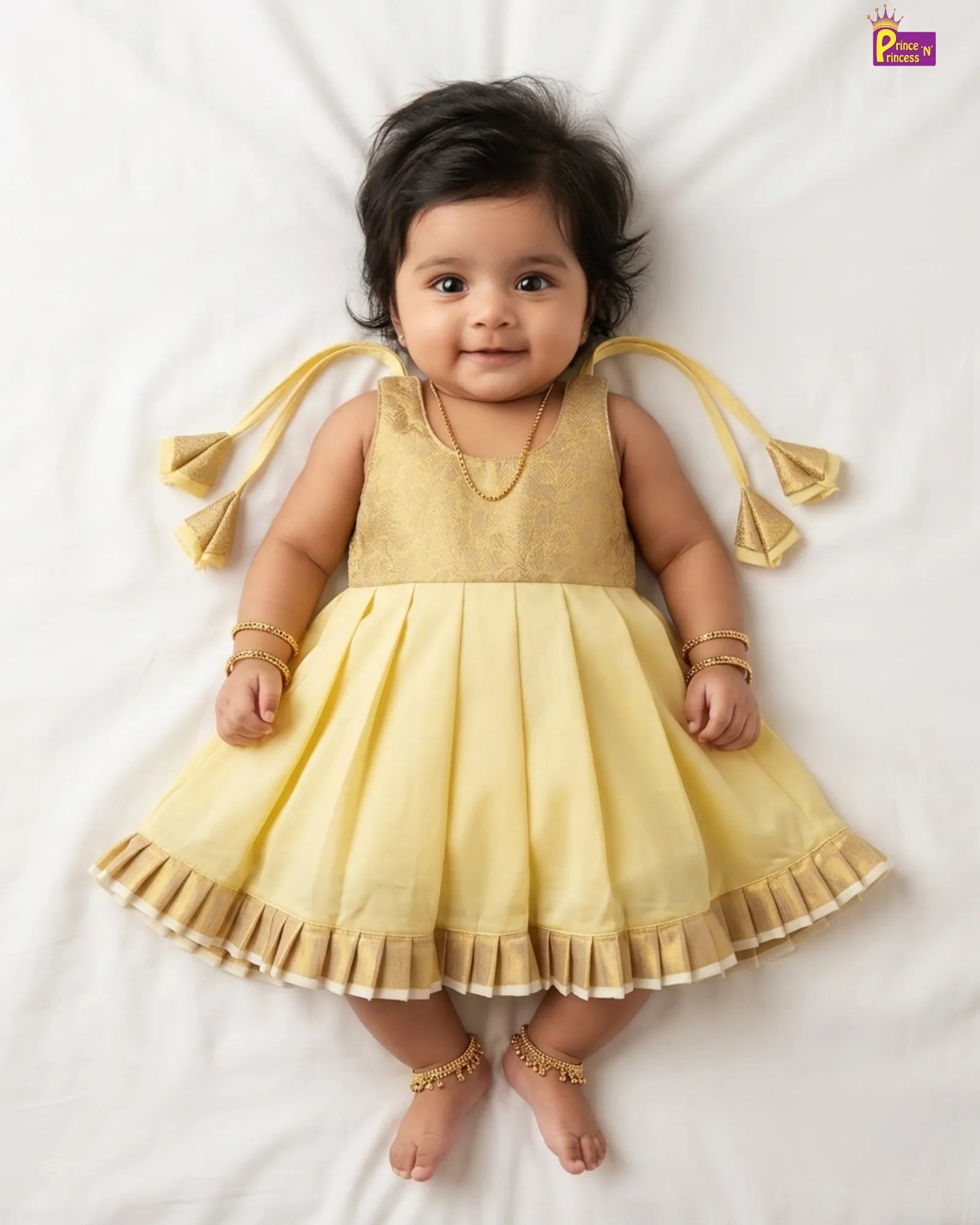 Newborn baby girl in yellow organza silk frock with gold brocade bodice and ruffle hem by Prince N Princess naming ceremony collection