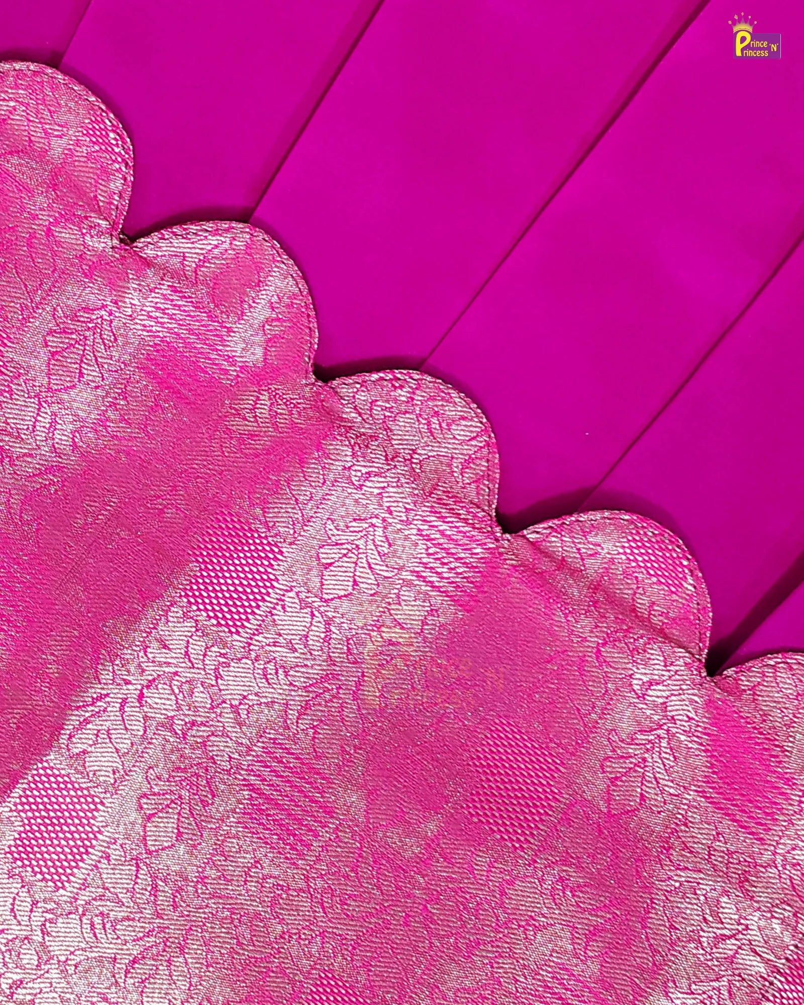 A close-up of a bright pink fabric with a scalloped edge and a lighter pink floral jacquard pattern, laid over a matching solid pink background.