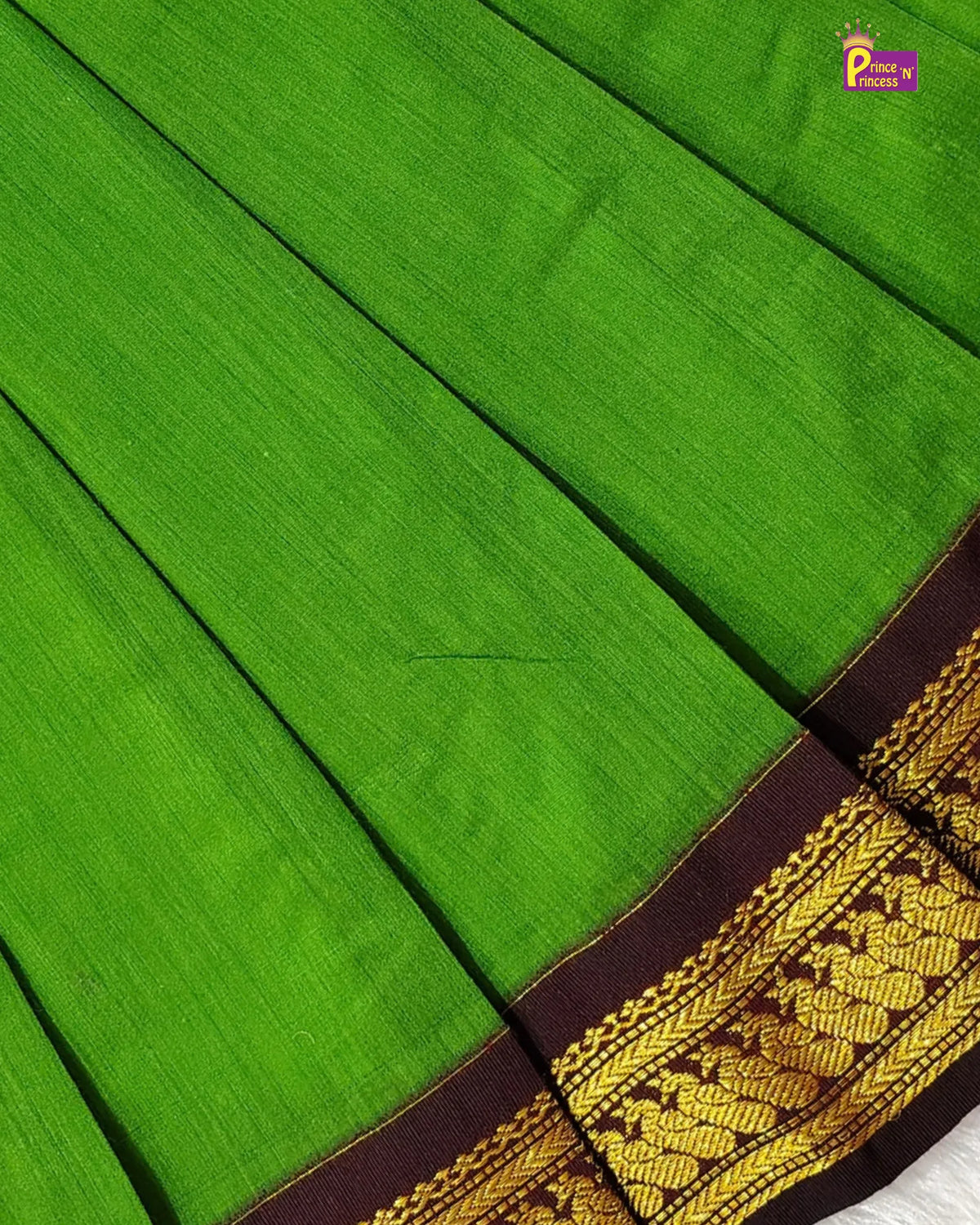 A close-up of a bright green silk saree with a dark brown border featuring intricate gold zari embroidery.