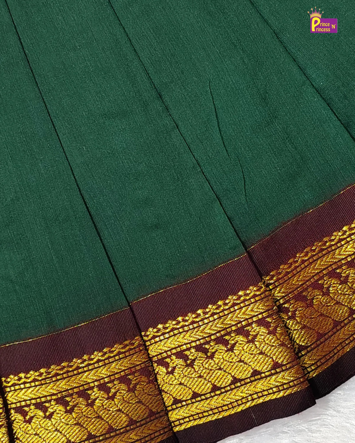 Close-up of a dark green fabric garment with a wide decorative border in deep maroon and gold zari embroidery, showing pleated folds and a small 'Pancham' logo in the top right corner.