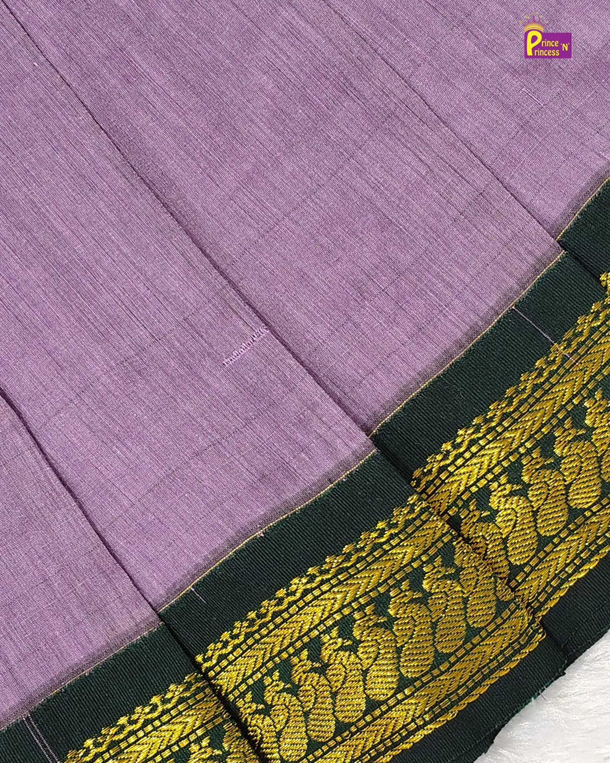 A close-up of a lavender purple woven fabric, likely a saree, featuring a dark green border with an intricate gold paisley and floral zari pattern.