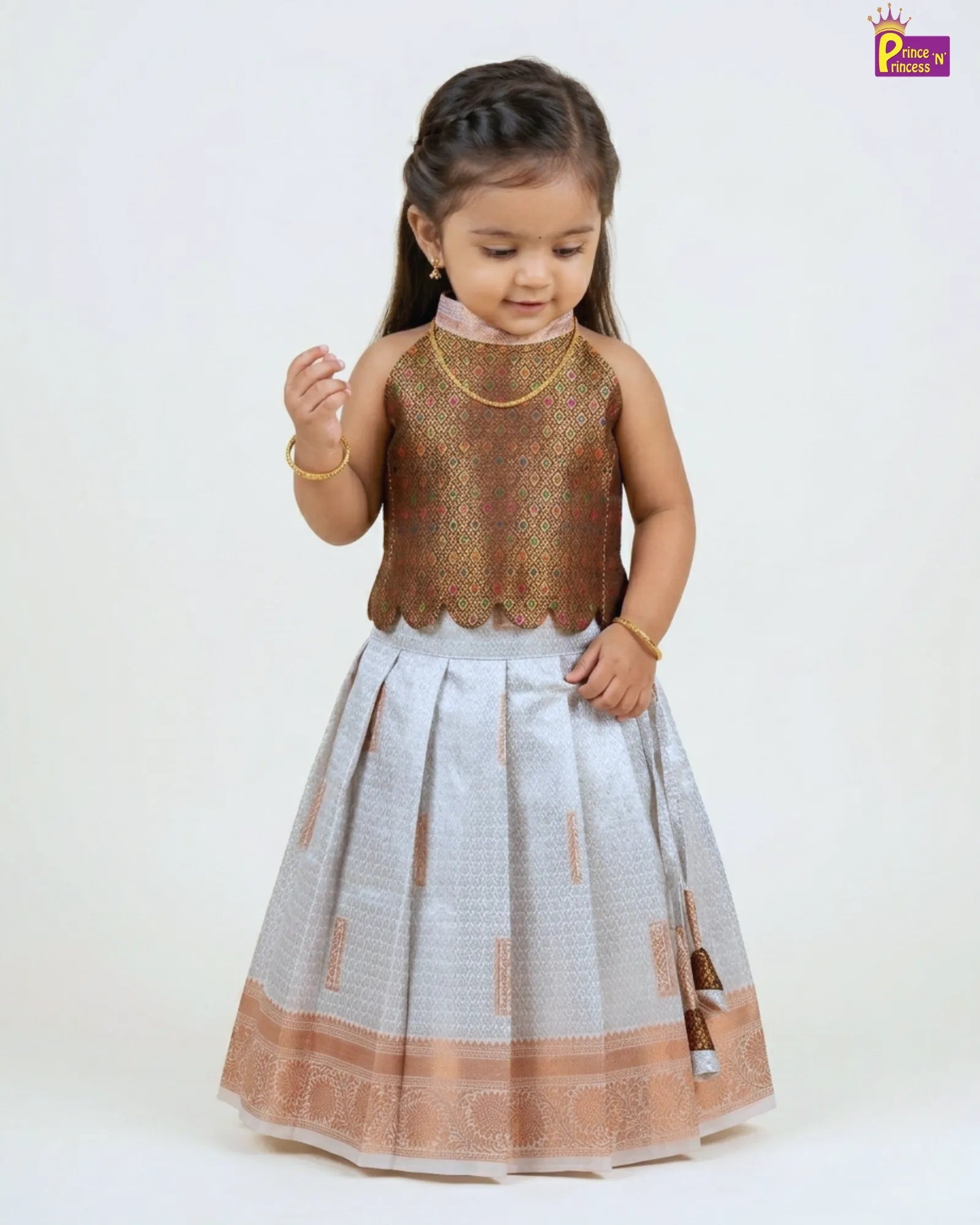 Young girl wearing a traditional outfit with a gold top and white skirt on a white background