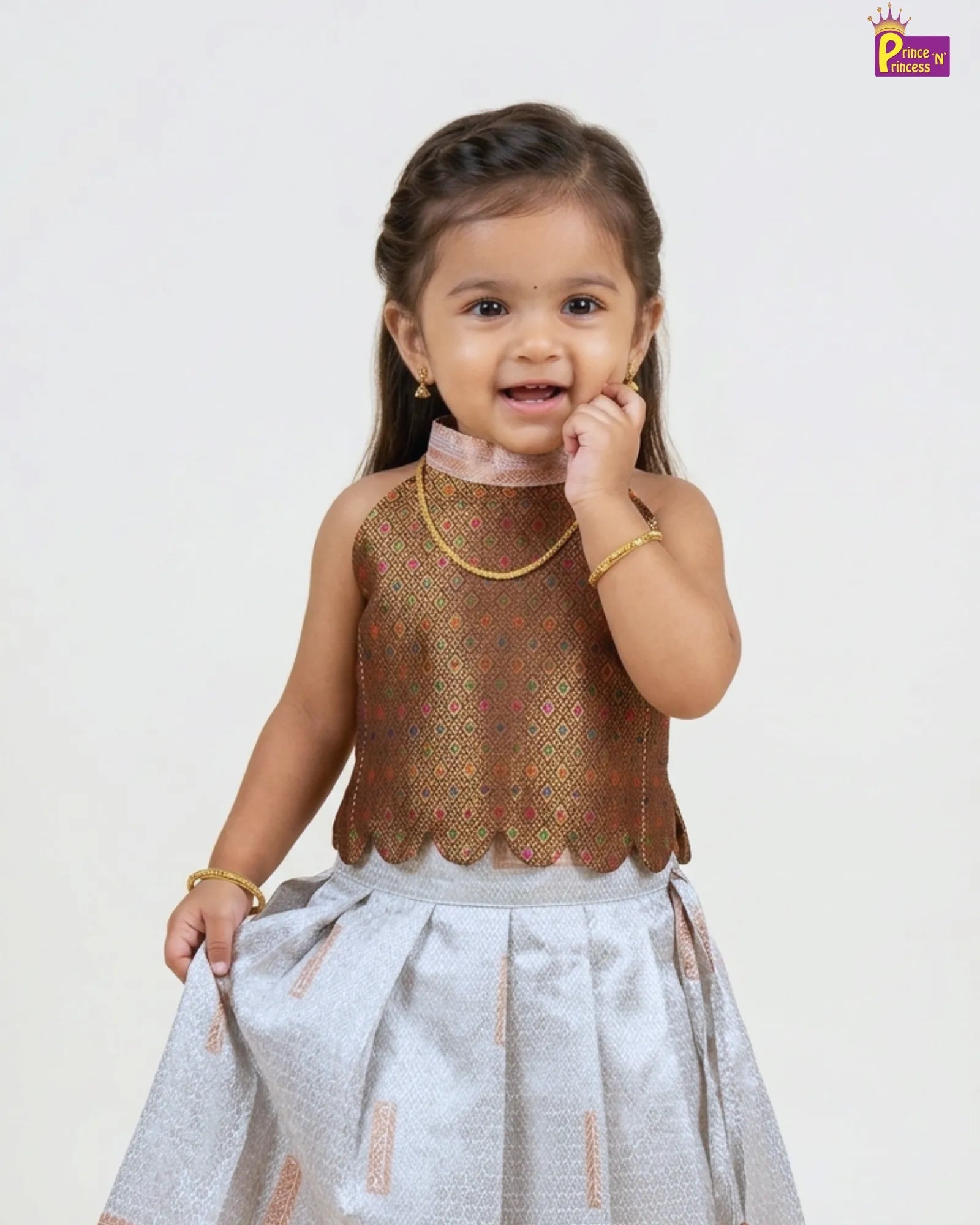 Young girl wearing a traditional outfit with a brown top and light-colored skirt on a white background.
