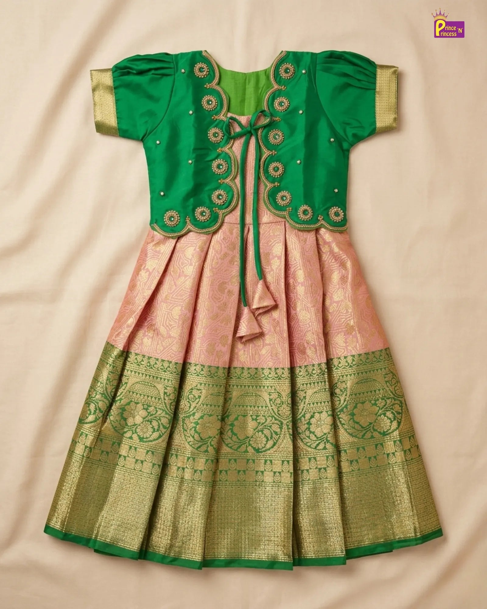 Green and pink traditional outfit with intricate patterns on a beige background