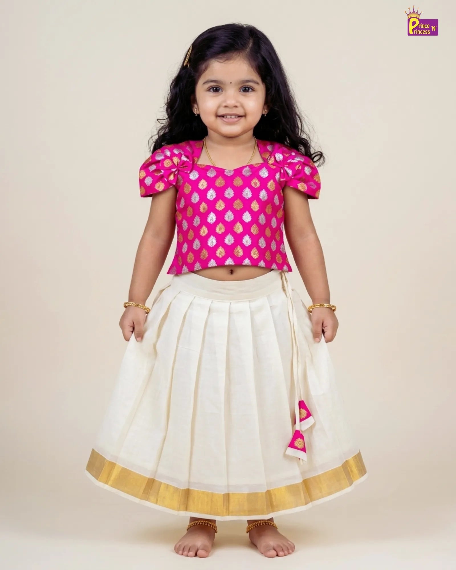 Young girl wearing a pink blouse with floral patterns and a white skirt with gold trim on a beige background.