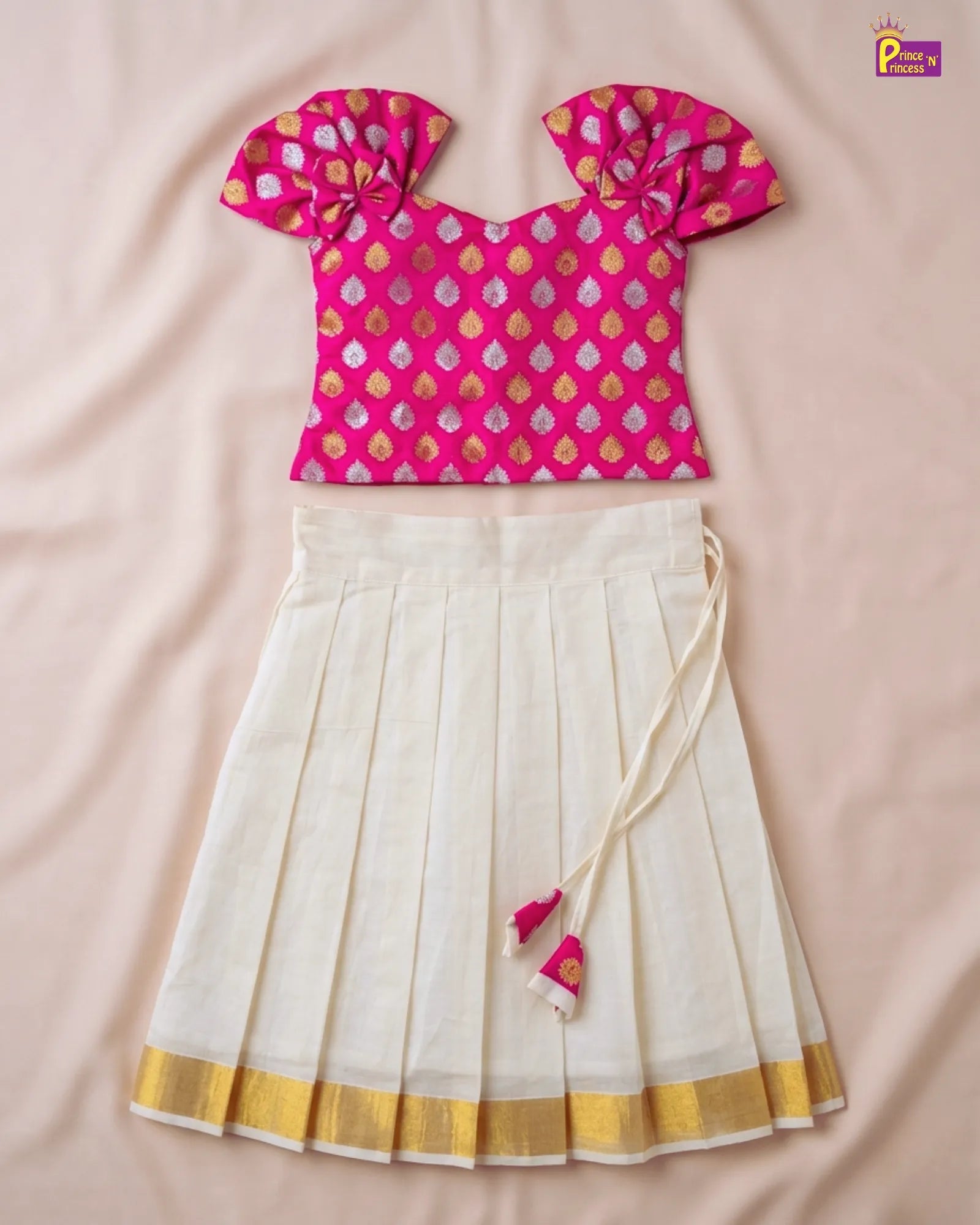 Pink and gold patterned top with a white skirt on a beige background