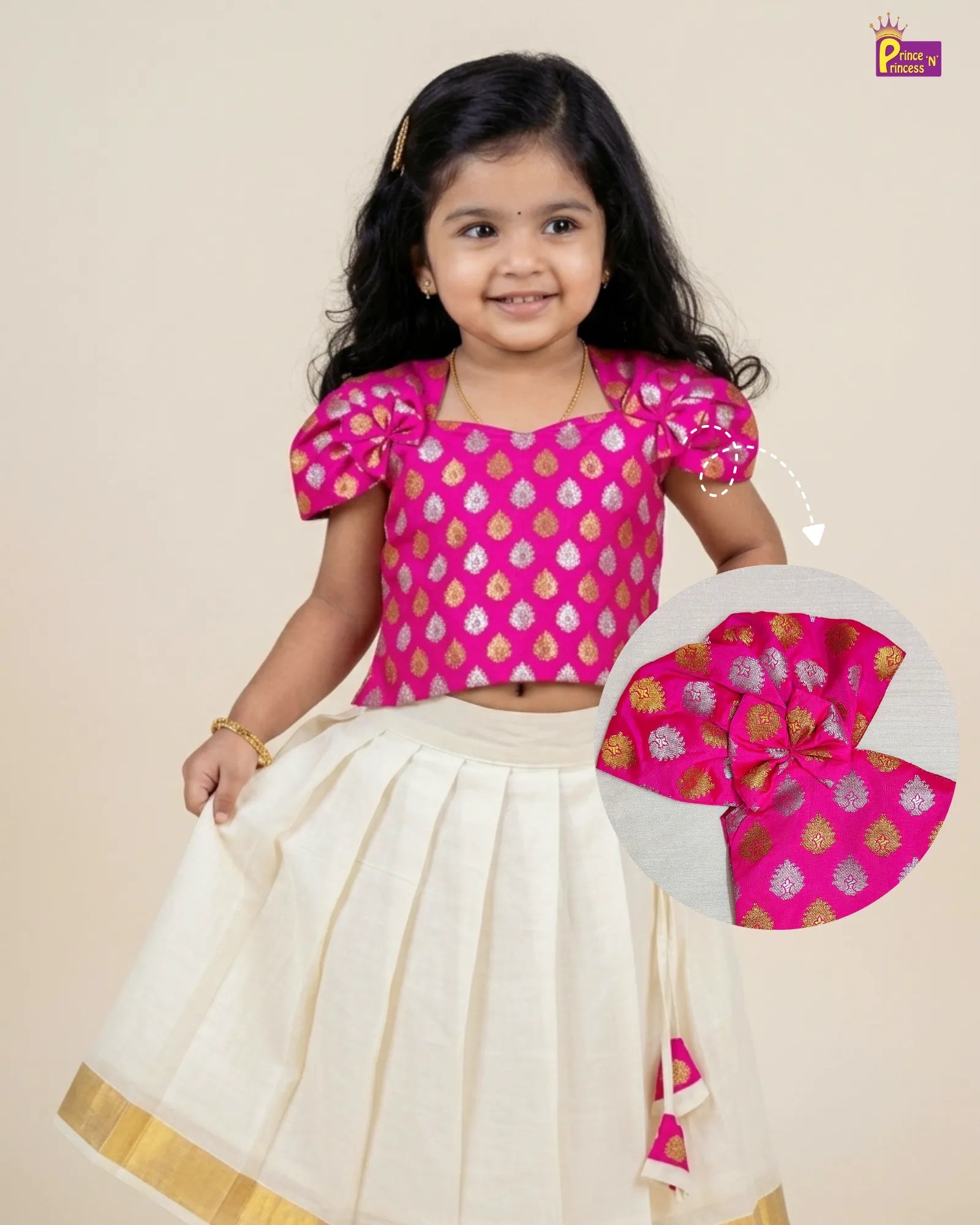 Young girl in a pink blouse with gold patterns and white skirt holding a matching pink and gold blouse.