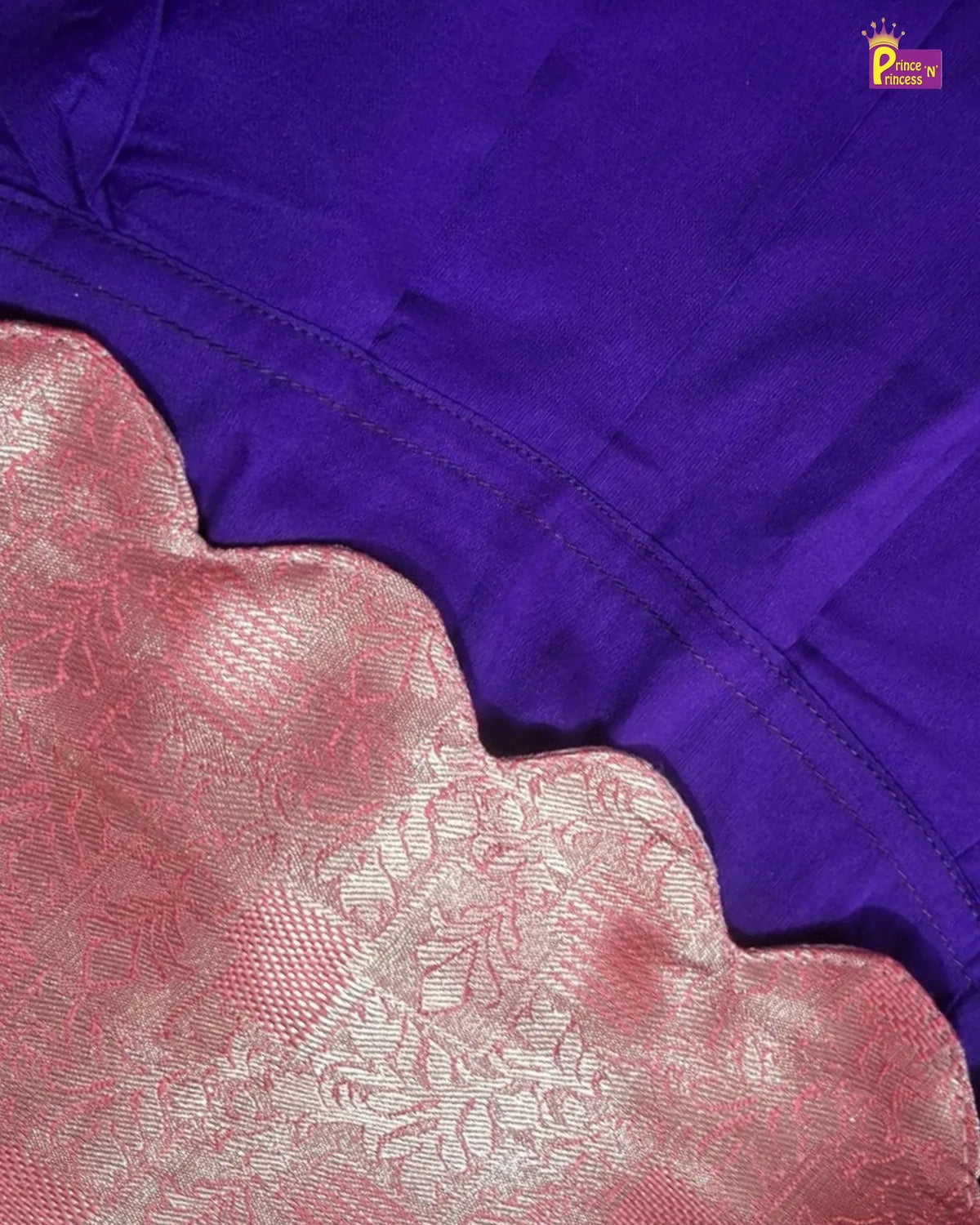 Close-up of a purple garment with a scalloped pink patterned border, showing fabric texture and stitching.