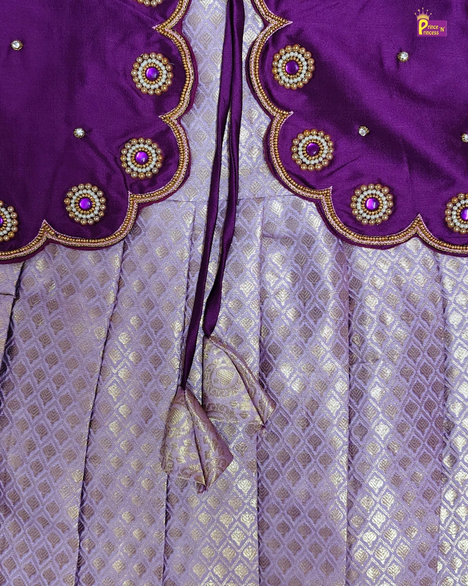 Purple blouse with intricate gold and bead detailing on a light purple fabric background