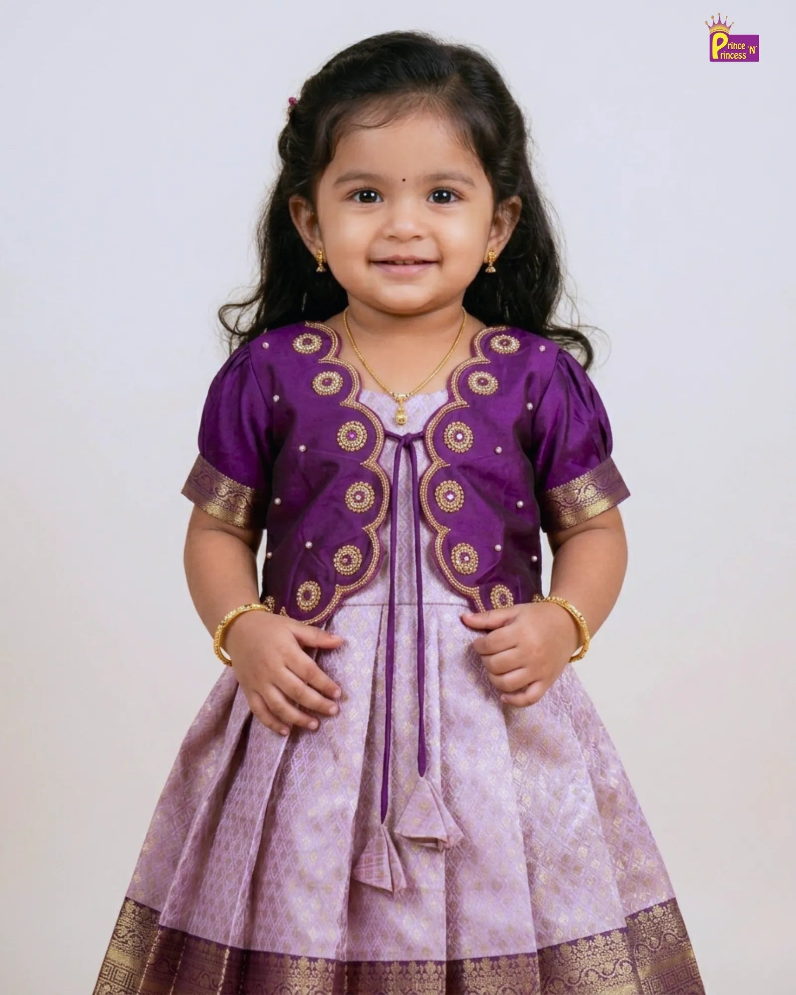 Young girl wearing a purple and gold traditional outfit on a white background