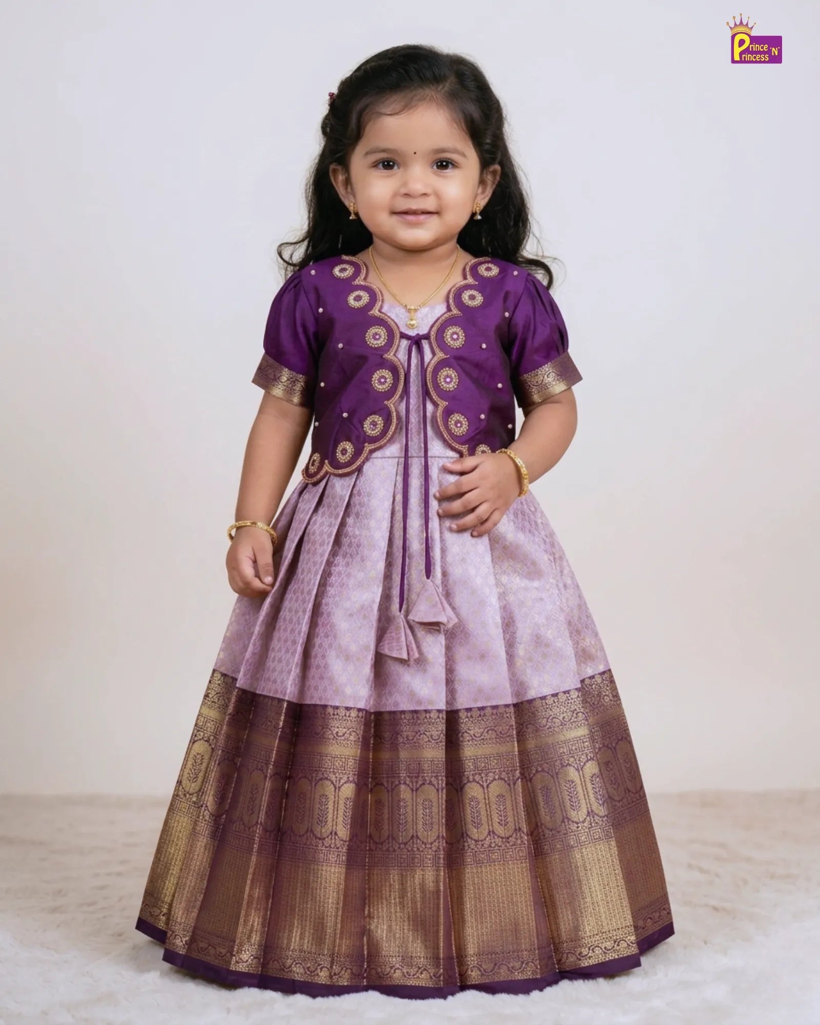 Young girl wearing a traditional purple and gold dress on a white background