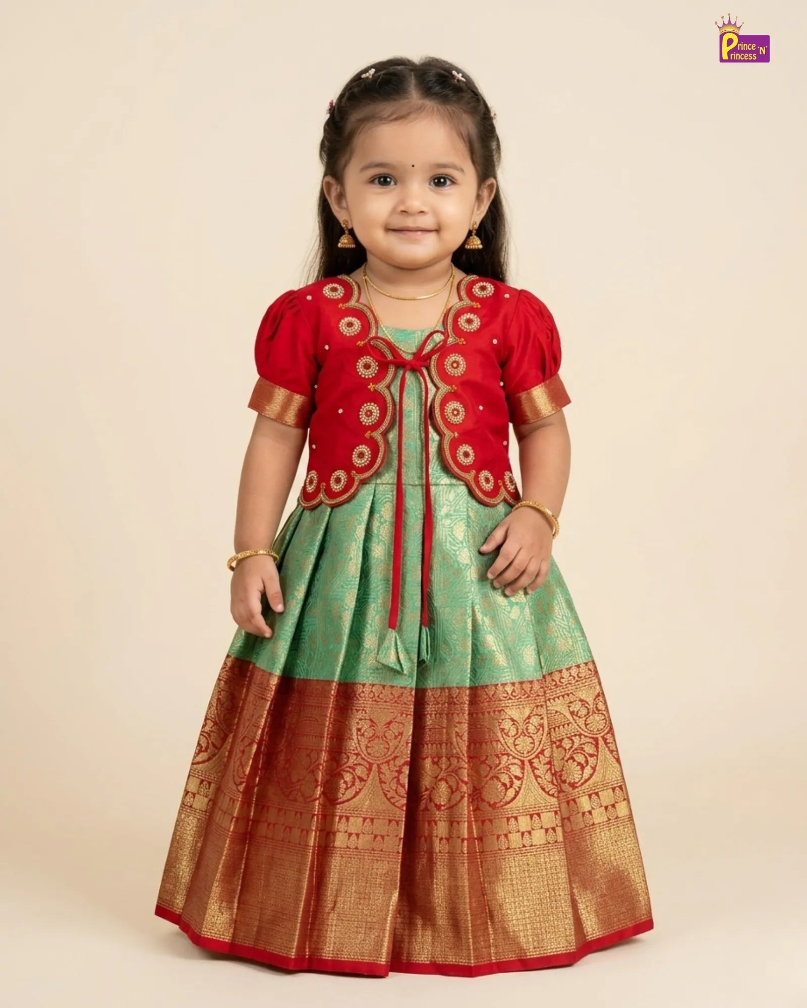 Young girl wearing a traditional outfit with a red blouse and green and gold skirt on a beige background.