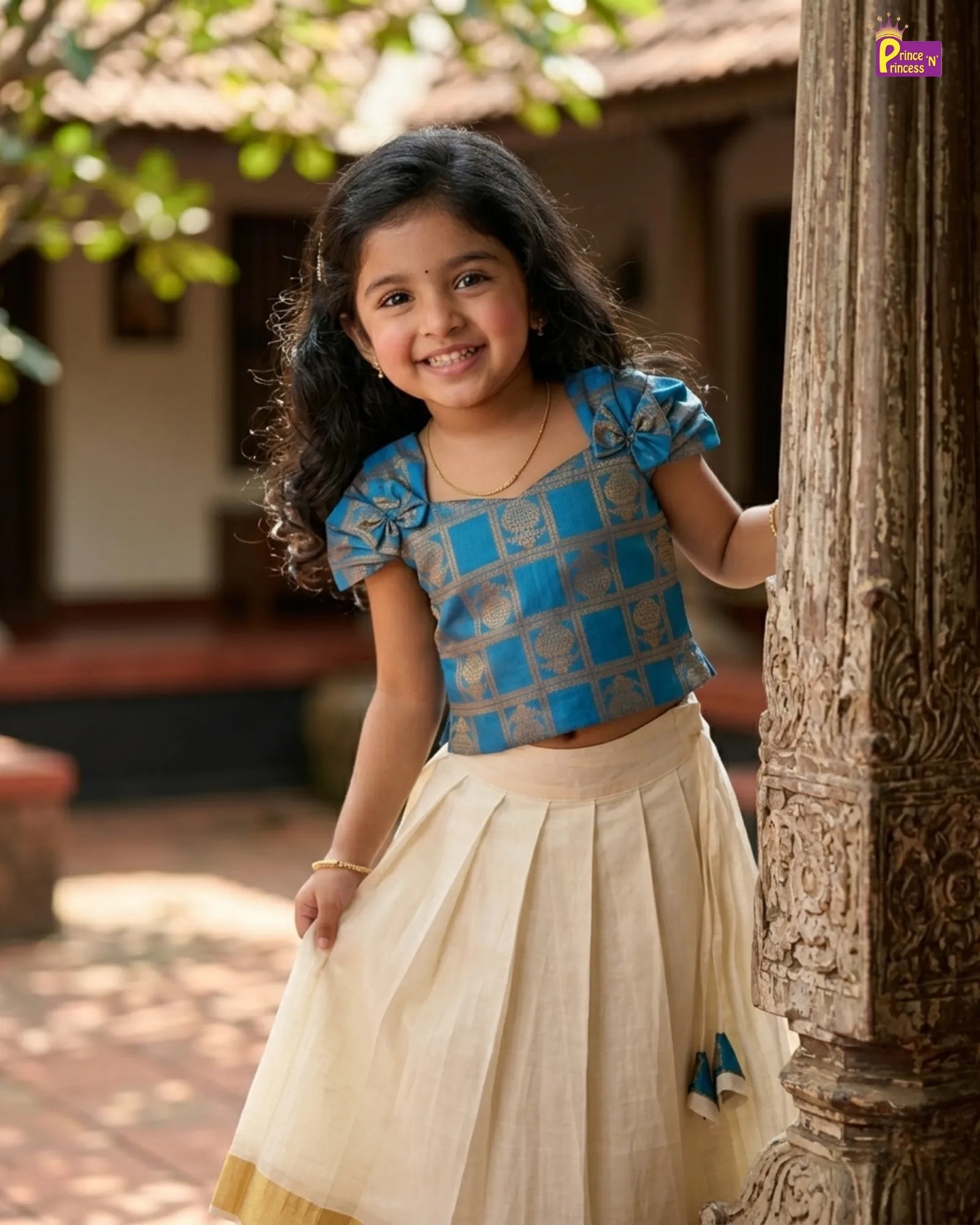Young girl in a blue and white traditional outfit standing outdoors.
