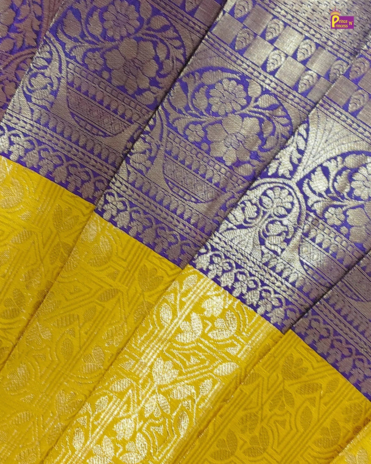 A close-up of a traditional Indian silk saree fabric, showing a rich purple border with intricate silver zari floral and vine patterns, paired with a bright yellow body featuring matching metallic silver woven motifs.