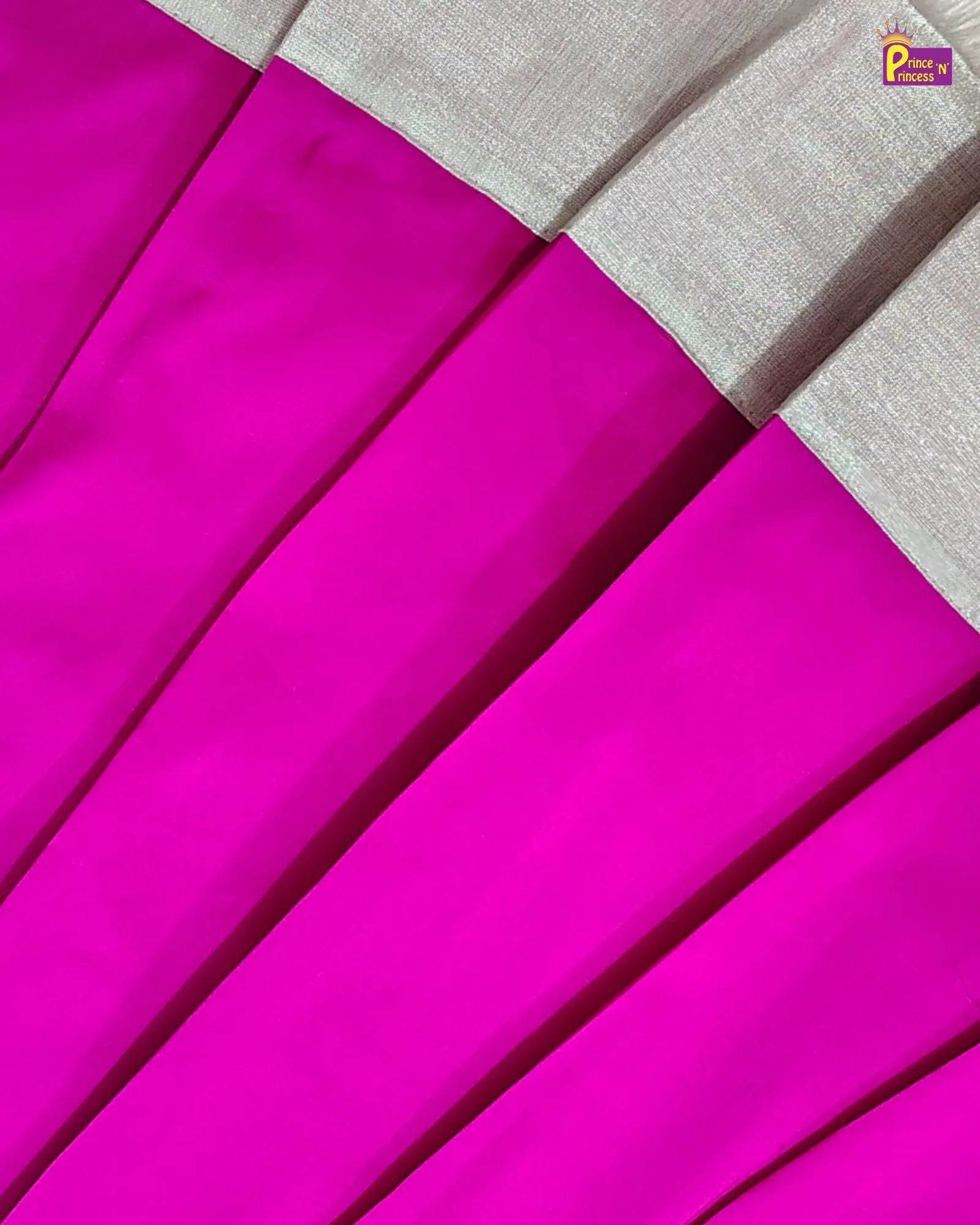 A close-up of a pleated fabric garment in vivid hot pink with a contrasting light beige border along the top edge.