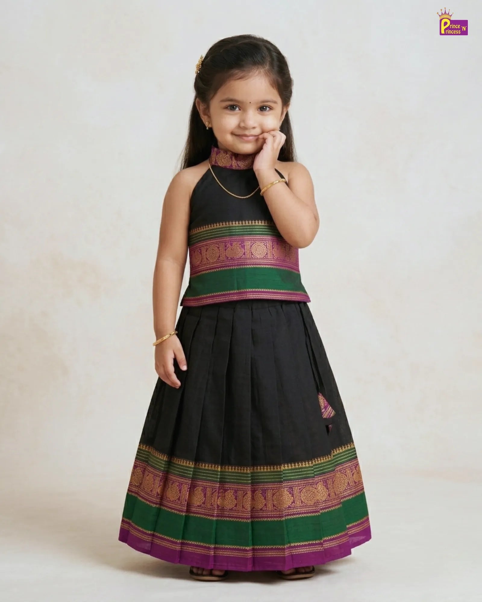 Young girl wearing a traditional black and green dress with colorful patterns on a white background