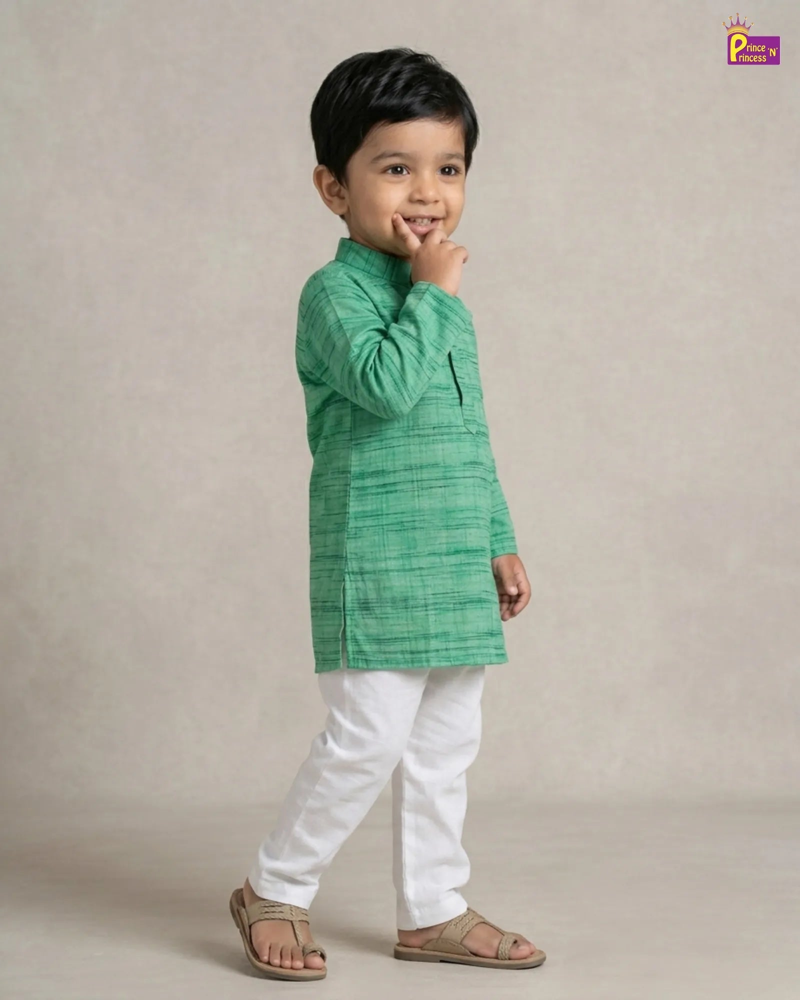 Child wearing a green kurta with white pants on a beige background