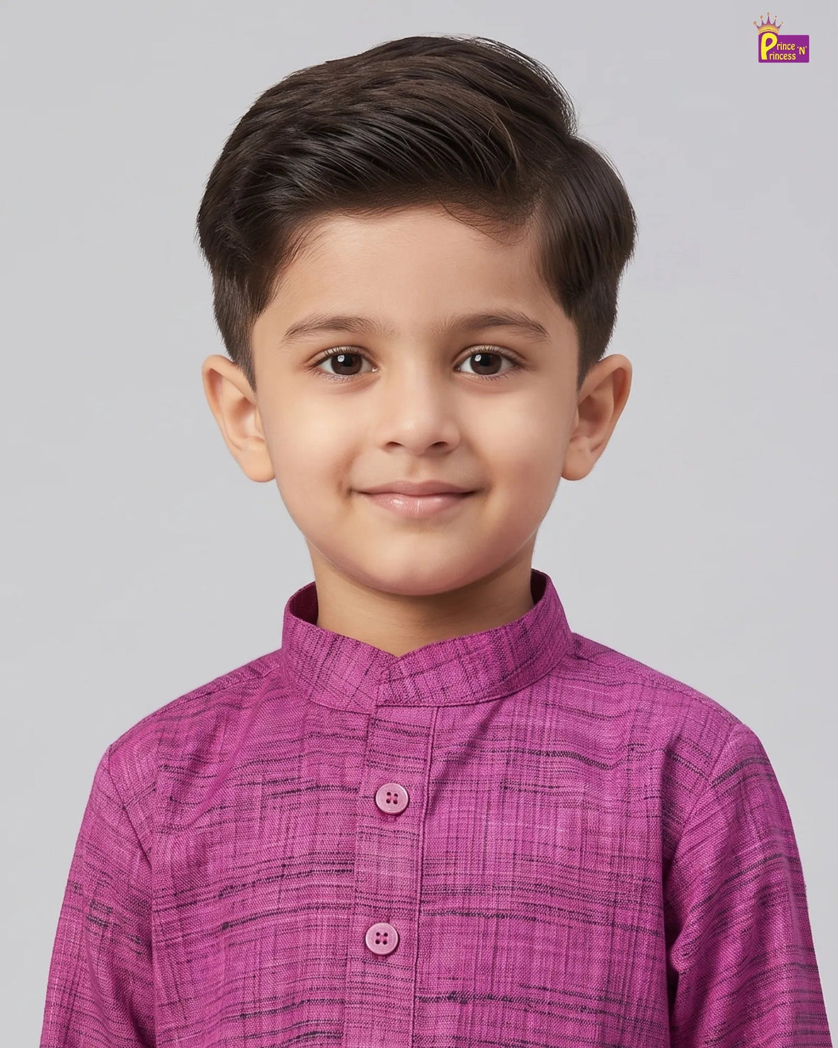 A young boy with dark brown hair wearing a textured magenta-pink traditional kurta with a mandarin collar, photographed against a solid light gray background.