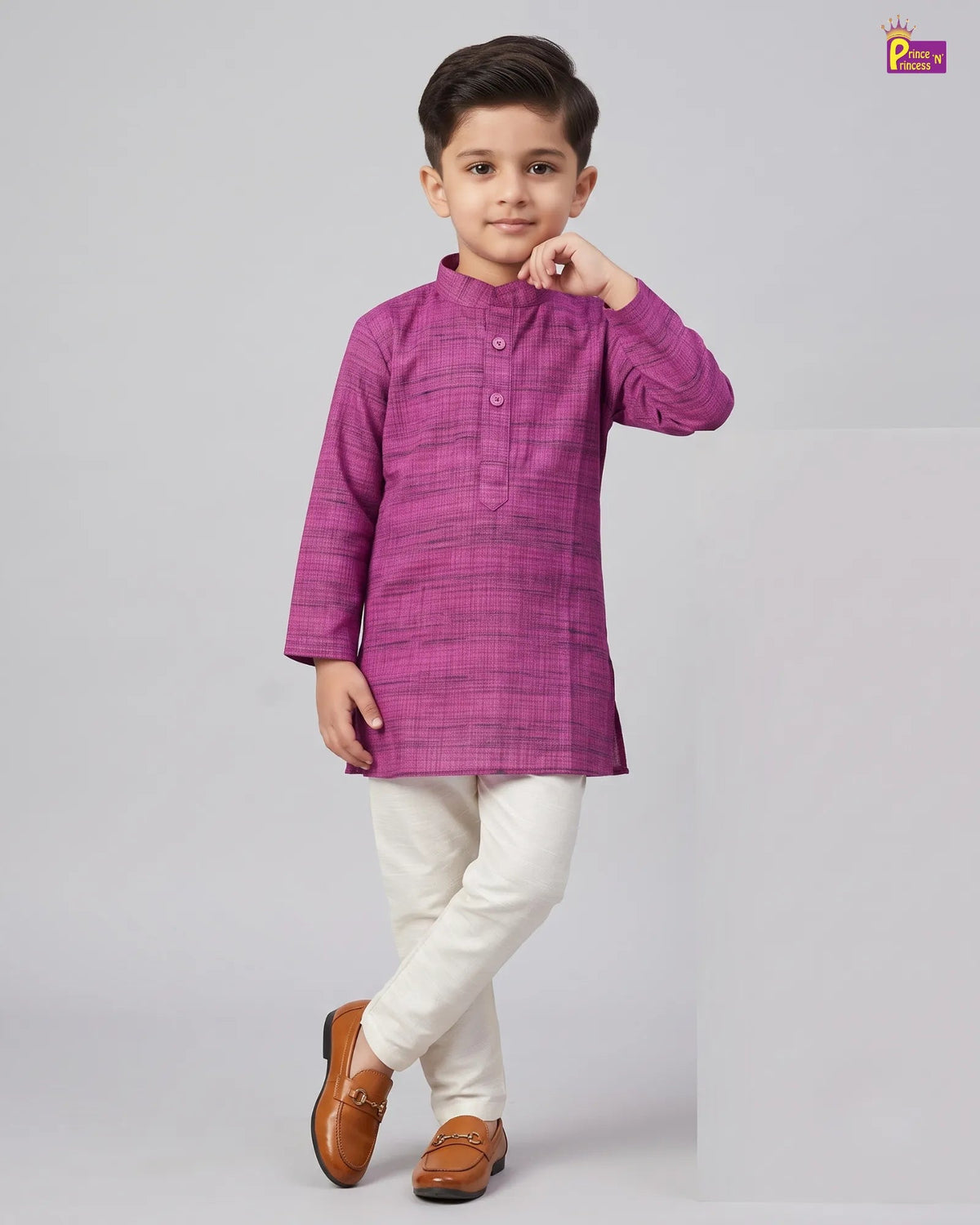 A young boy modeling a magenta-purple long-sleeve kurta with a subtle grid pattern, paired with off-white trousers and brown loafers, against a light gray studio background.