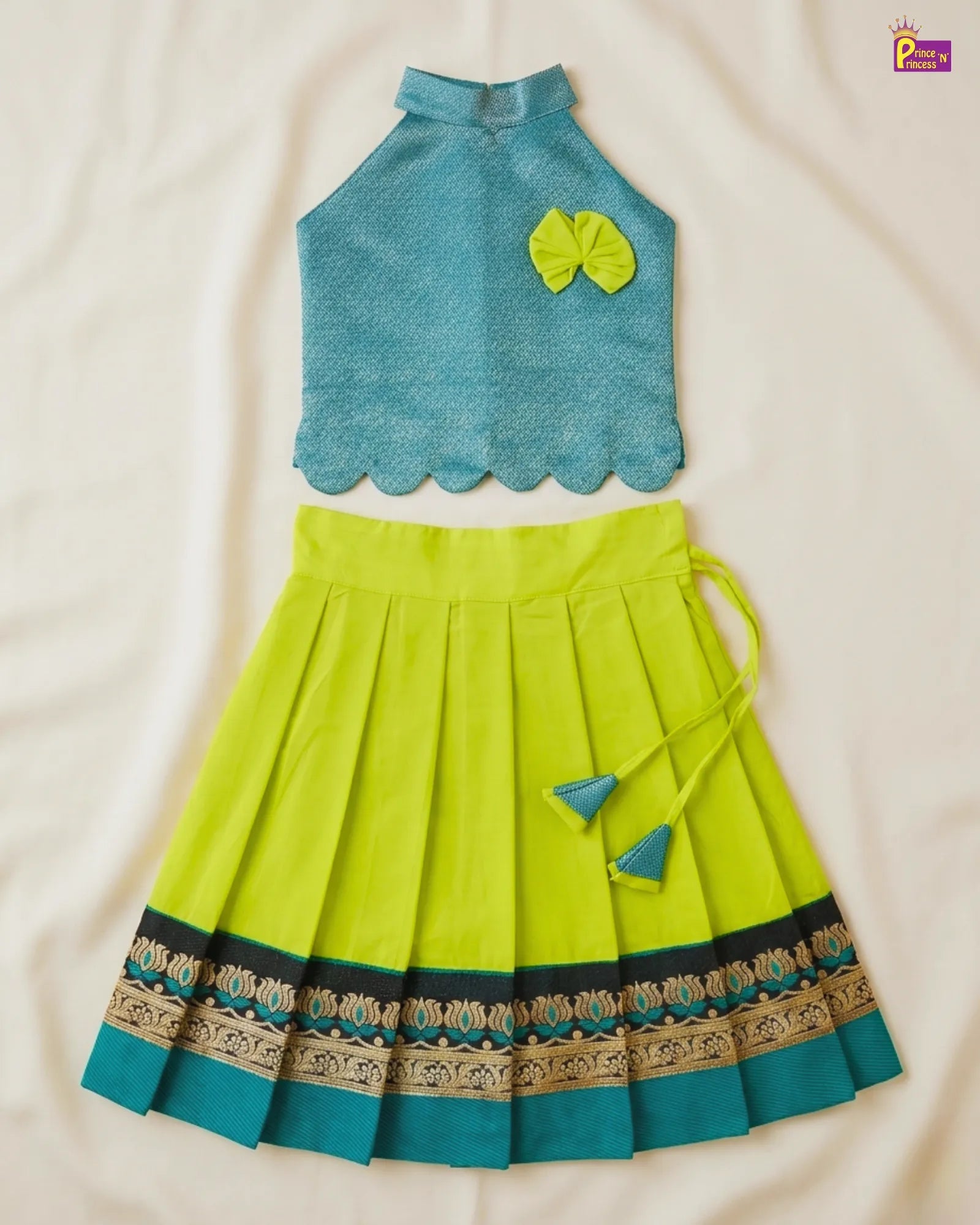 Green and blue traditional outfit with a top and pleated skirt on a beige background