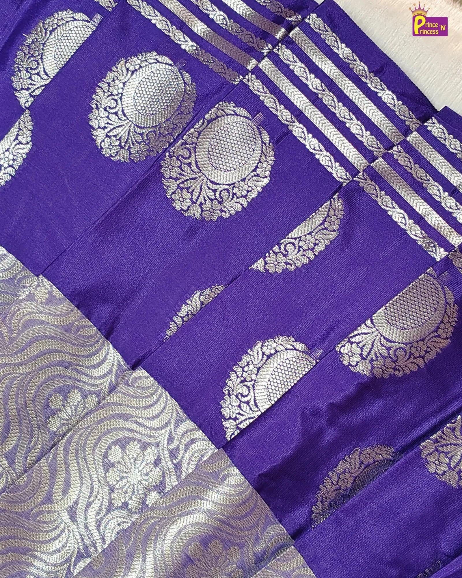 Purple saree with silver patterns and a brand logo in the corner