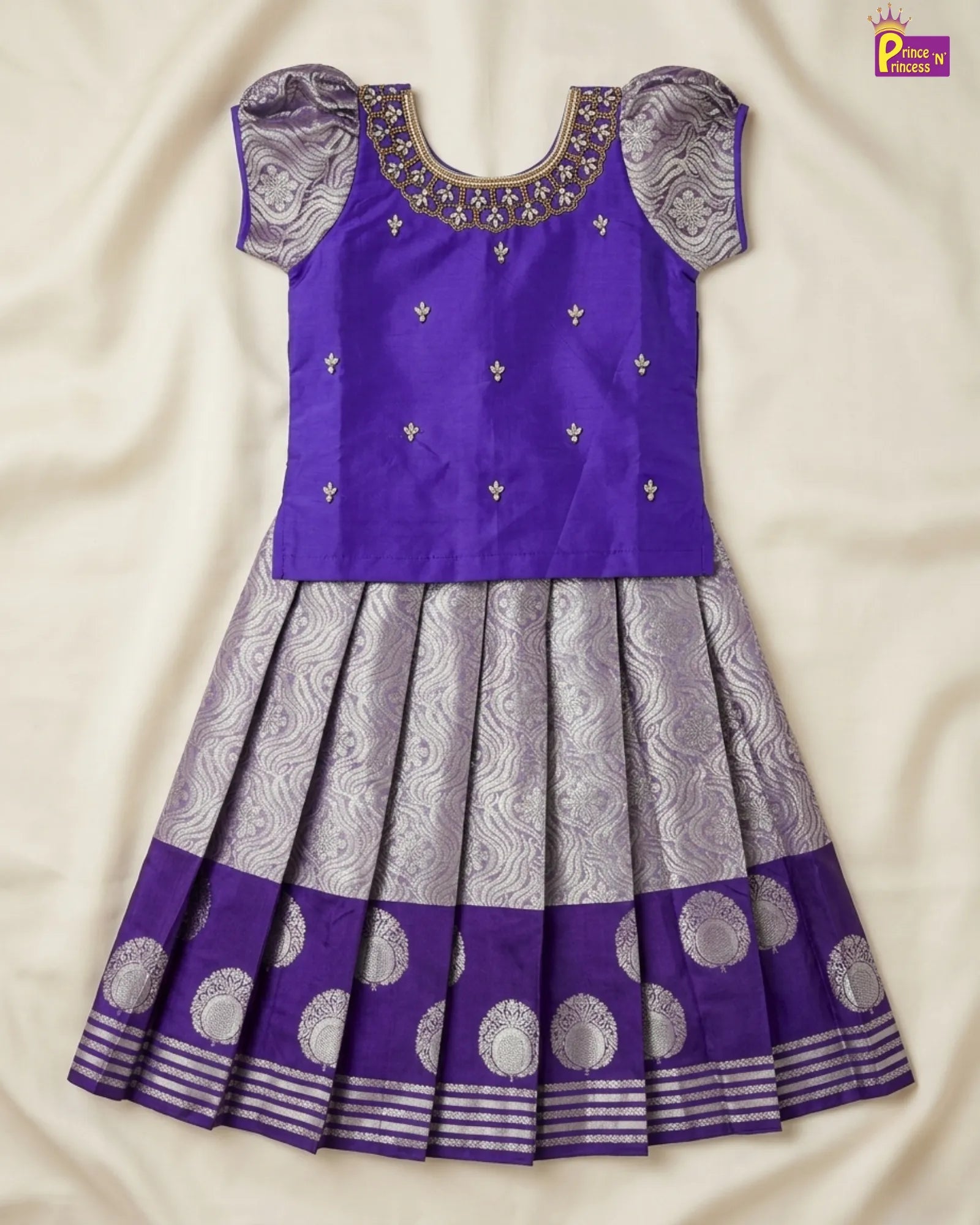 Purple and gray traditional dress with intricate patterns on a beige fabric background