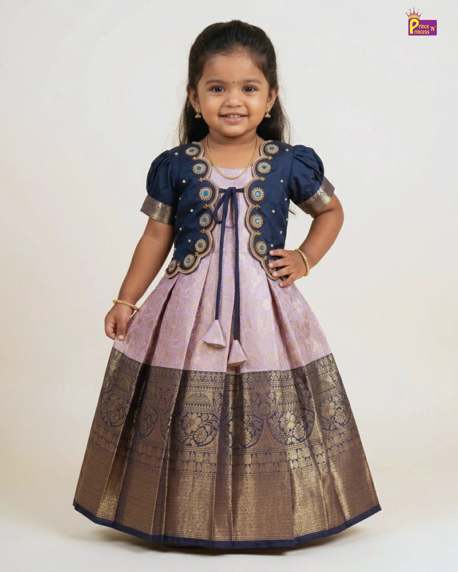 Young girl wearing a traditional outfit with a navy blue and brown design on a white background