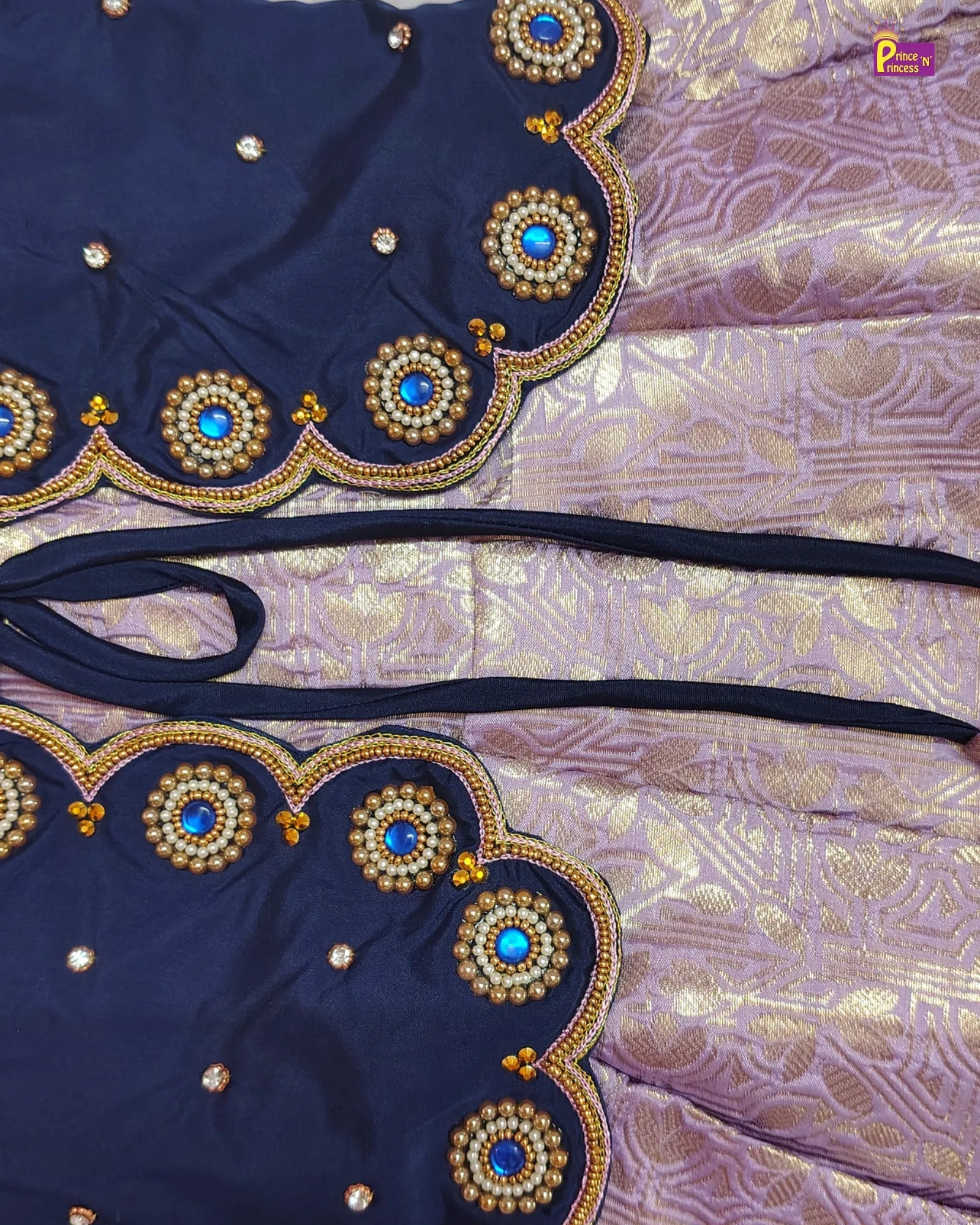 Navy blue fabric with gold and blue bead embellishments on a patterned purple background