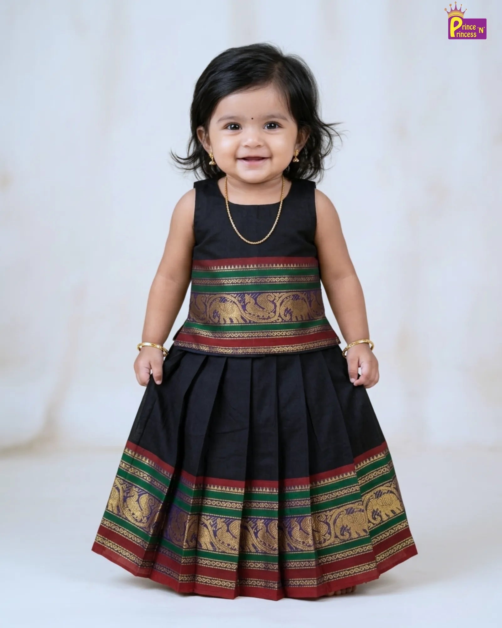 Child wearing a traditional black dress with colorful patterns on a white background