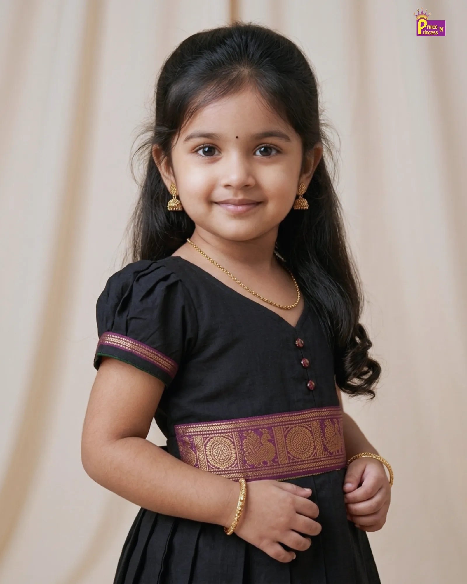 Young girl in a black traditional outfit with gold accents against a beige background