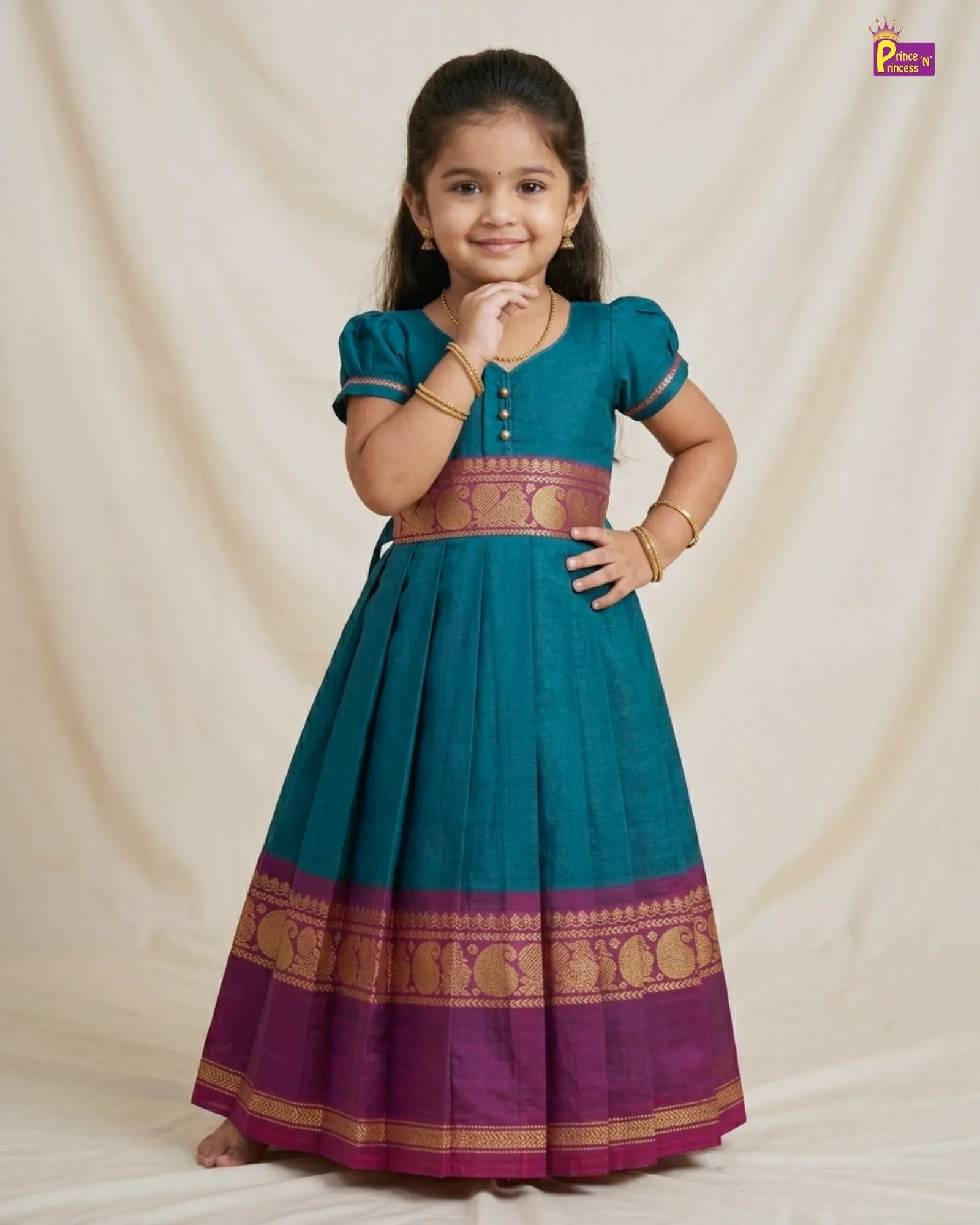 Young girl wearing a traditional teal and purple dress with a plain background