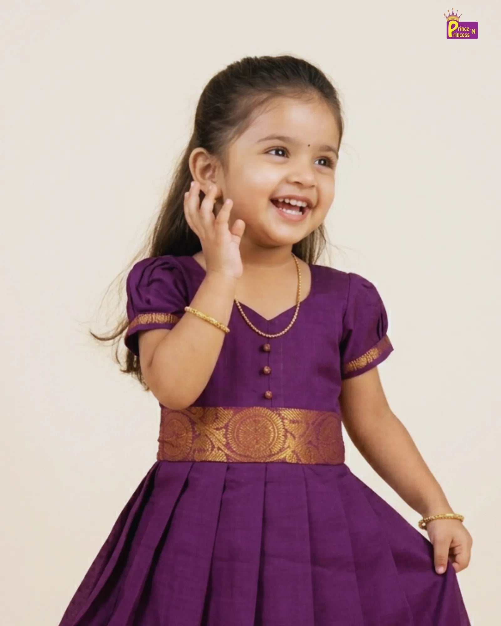 Young girl wearing a purple traditional outfit with gold details on a beige background